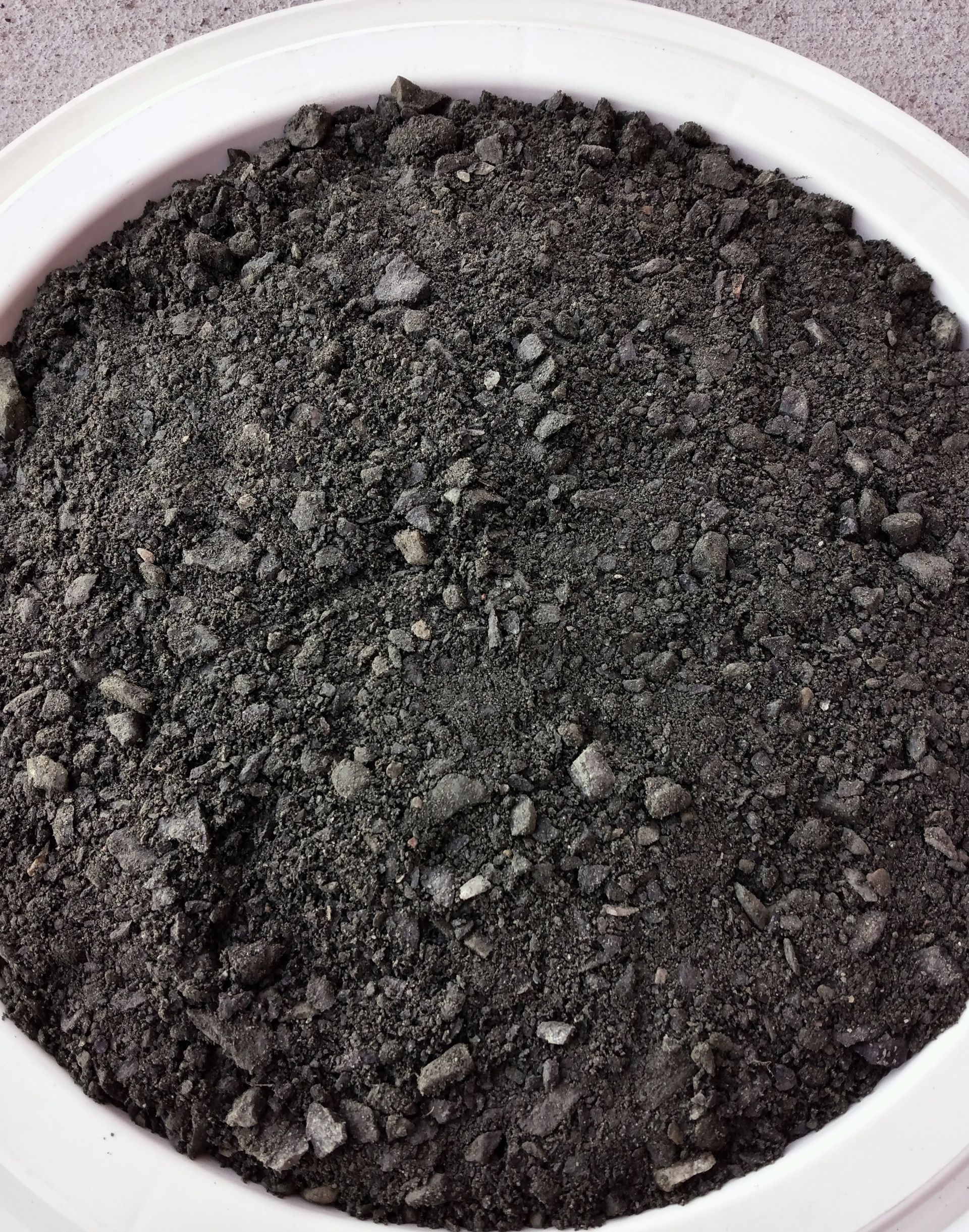 A white bowl filled with black rocks on a table.