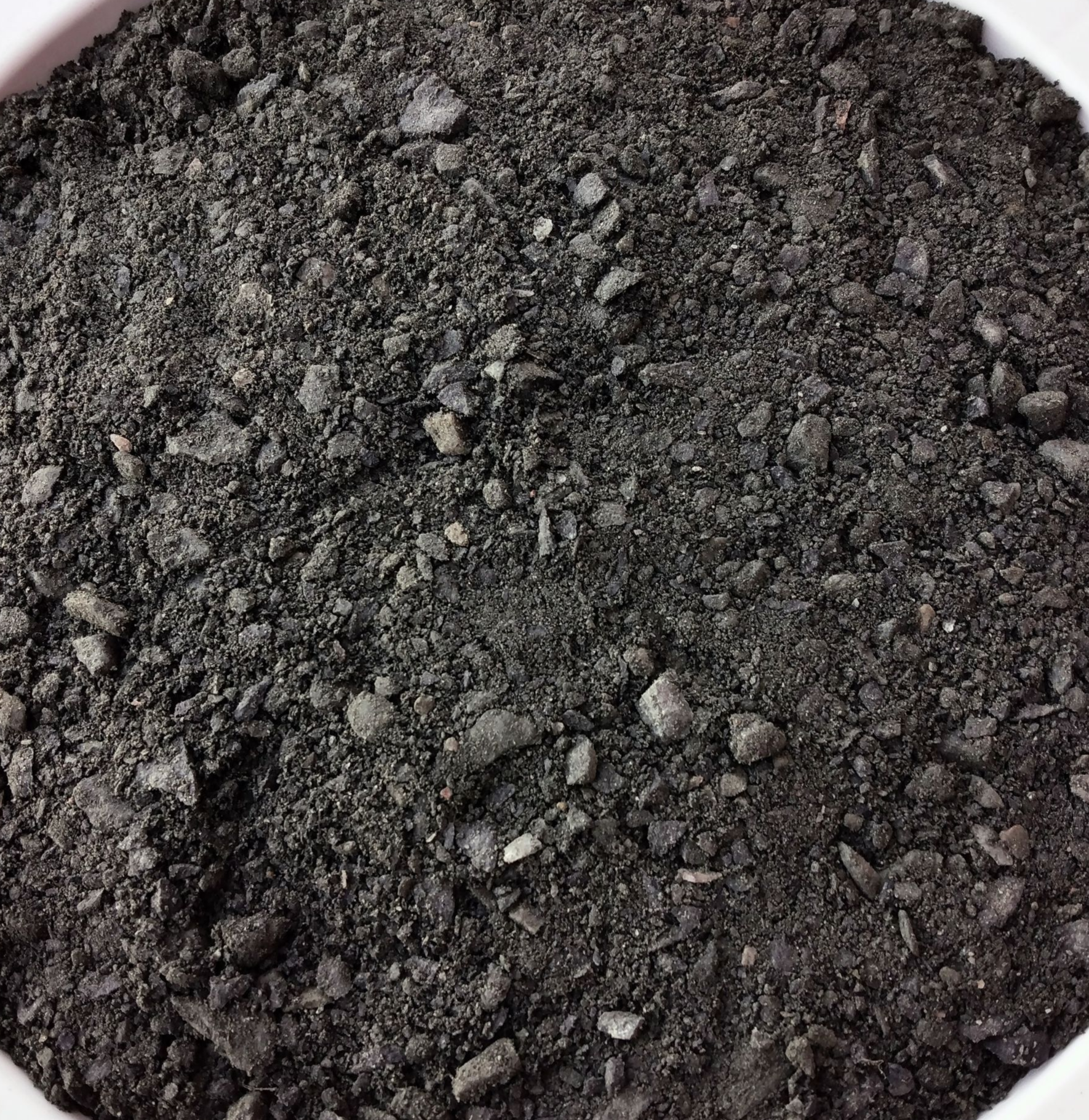 A white bowl filled with black rocks on a table.