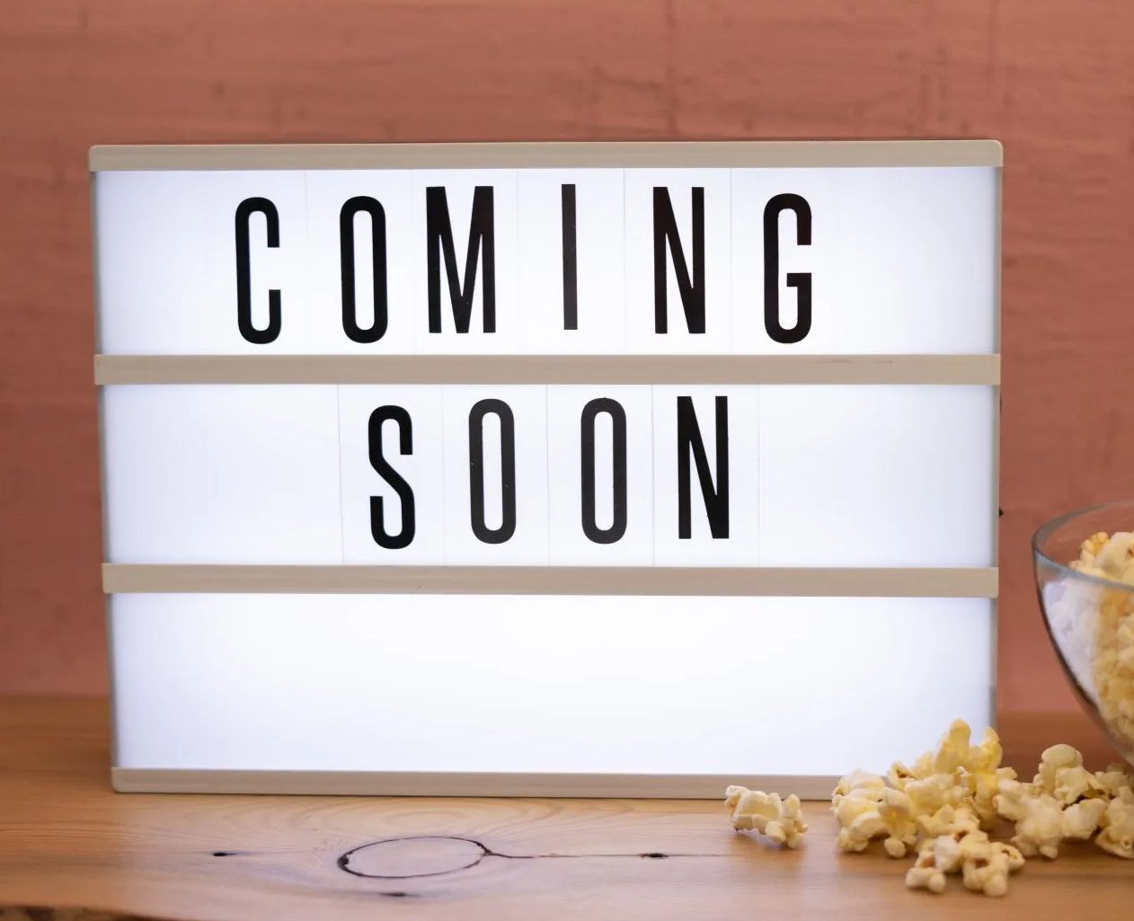 A light box that says `` coming soon '' next to a bowl of popcorn.