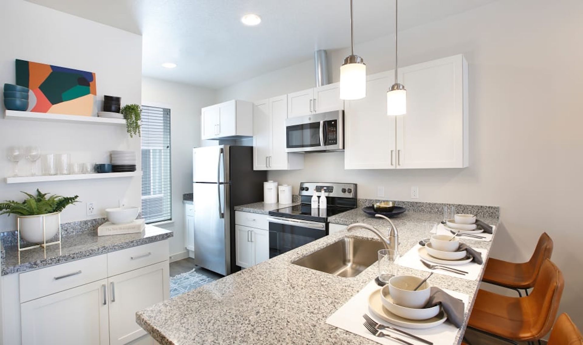 Modern kitchen with white cabinets, stainless steel appliances, and a granite countertop bar.