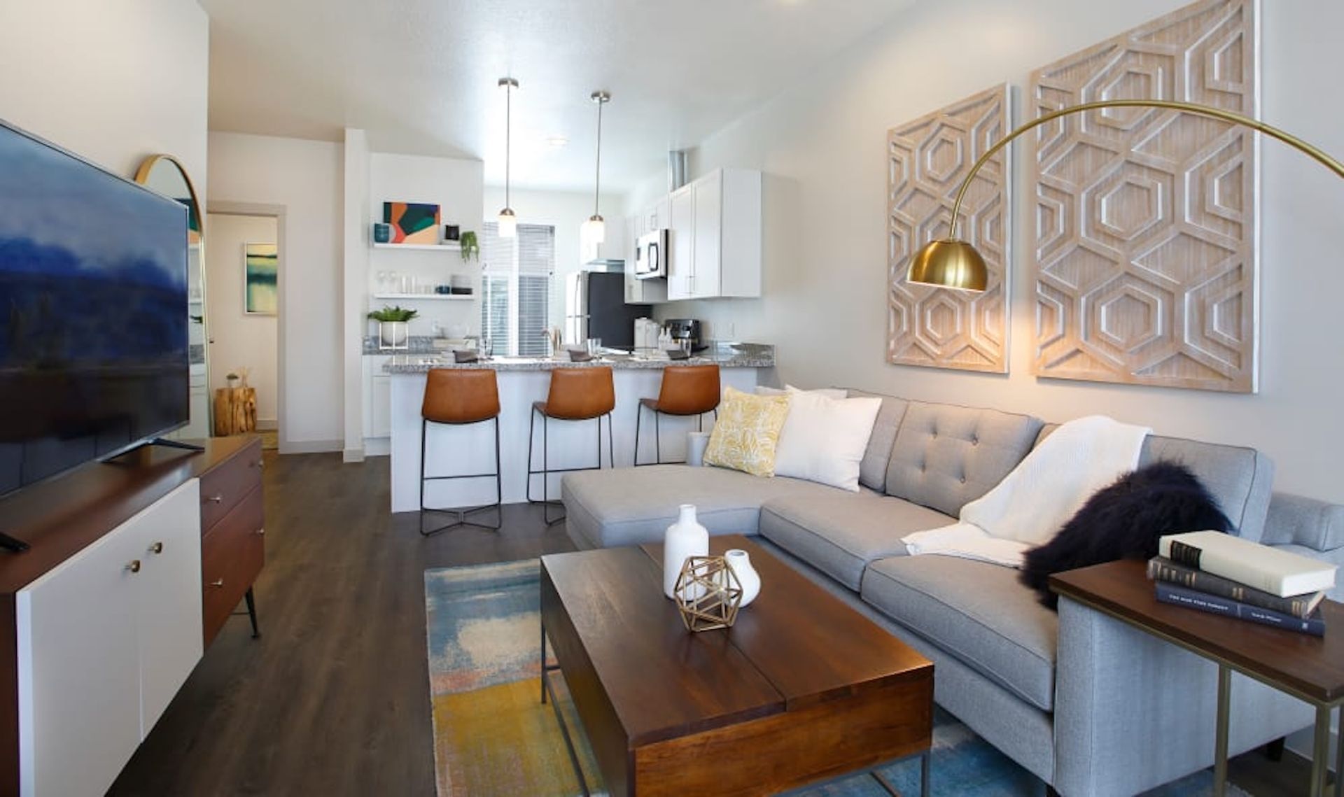 Modern living room with open kitchen, gray sectional sofa, and wood accents.