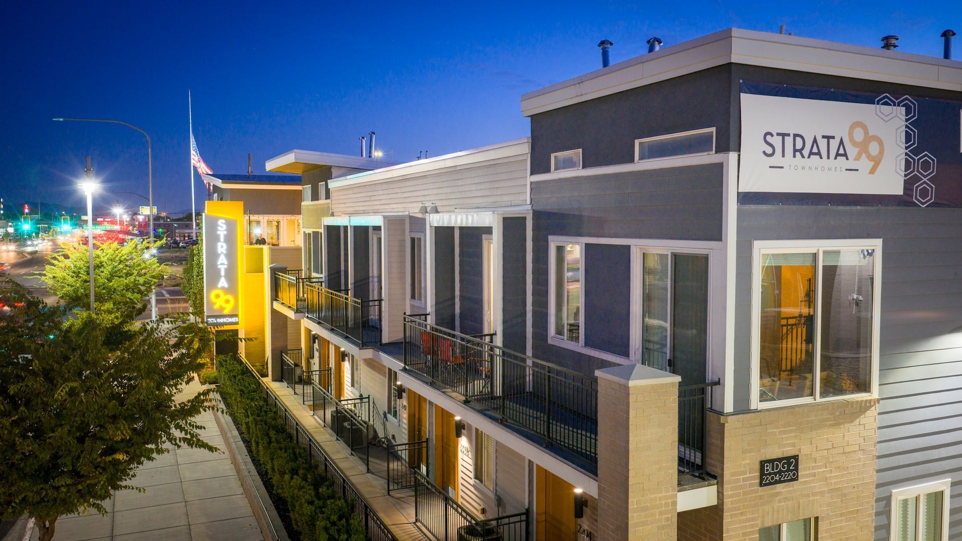 Strata 89 apartments at dusk; modern building with balconies, yellow and gray accents, street lights.