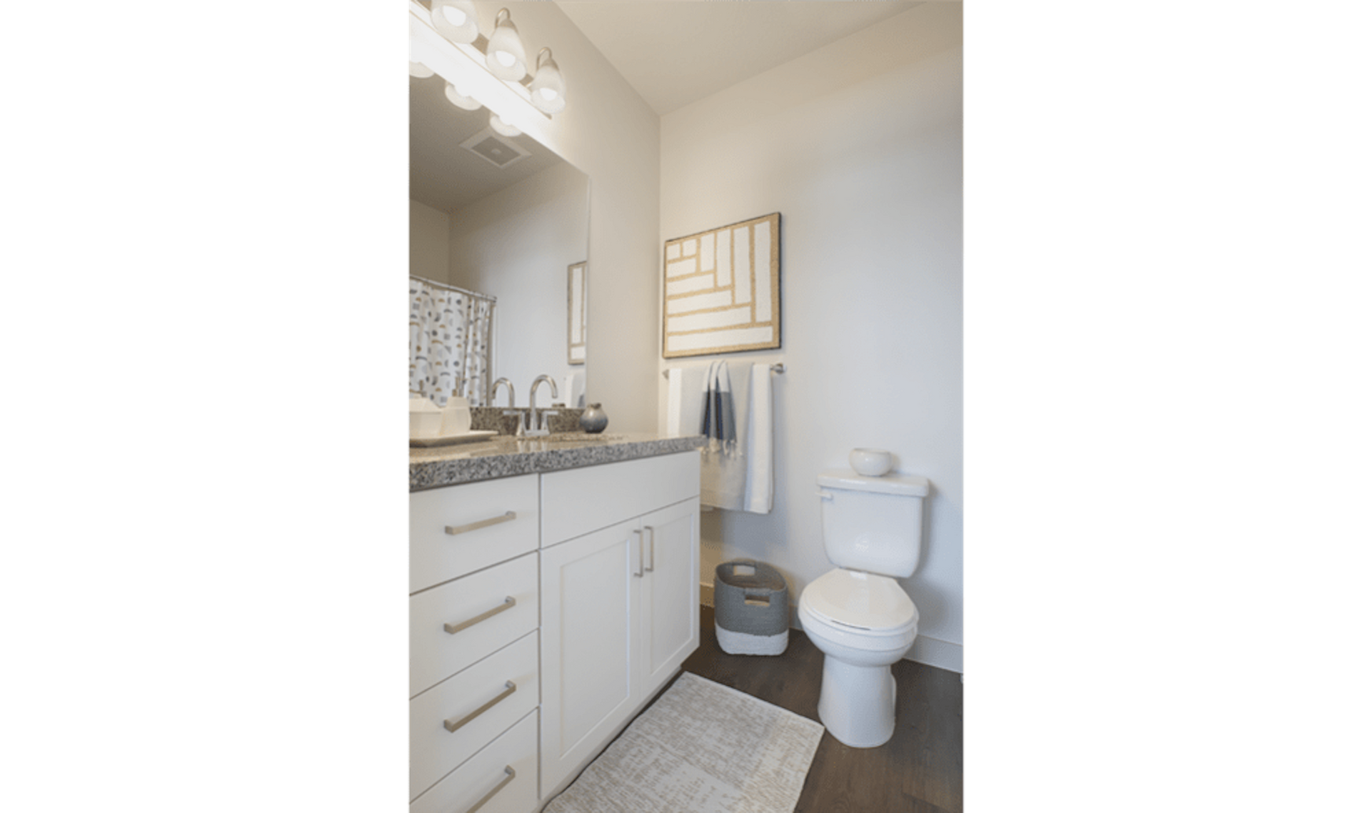 Bathroom with white vanity, toilet, and abstract wall art.