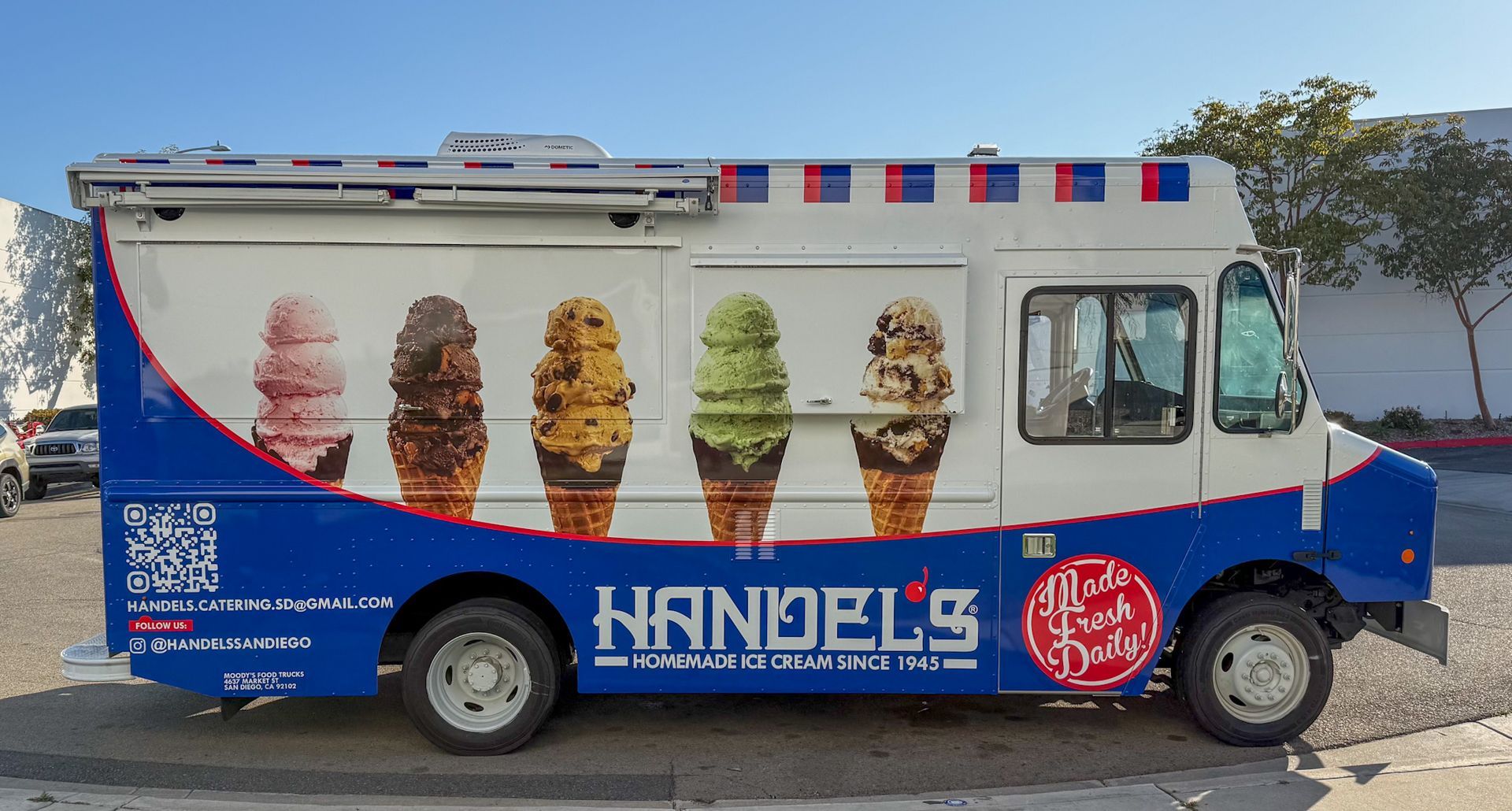 Handel's ice cream truck with ice cream cone graphics and blue and red trim, parked outside.