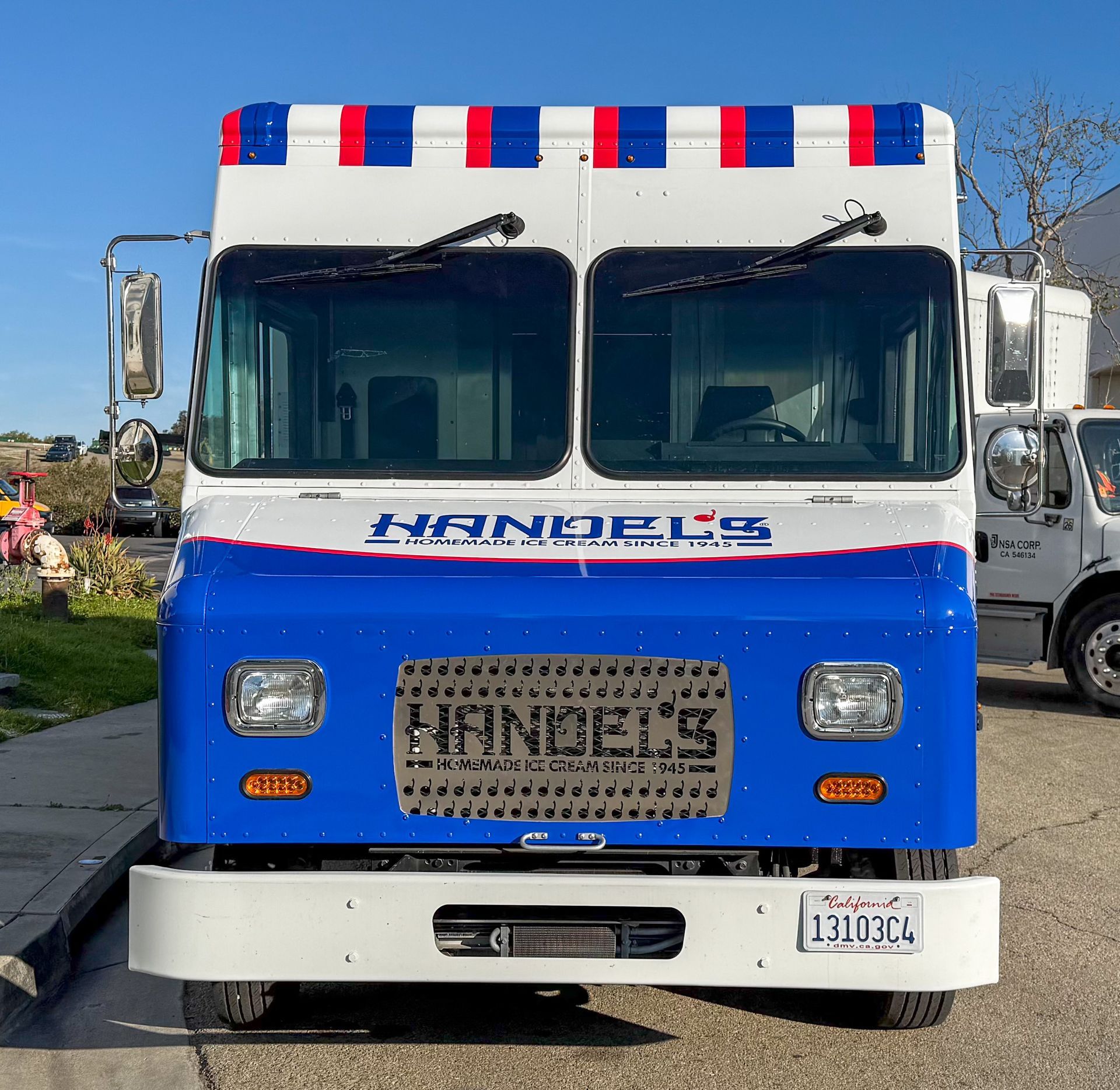 A blue and white Handel's ice cream truck with the Handel's logo. It's parked on a sunny street.