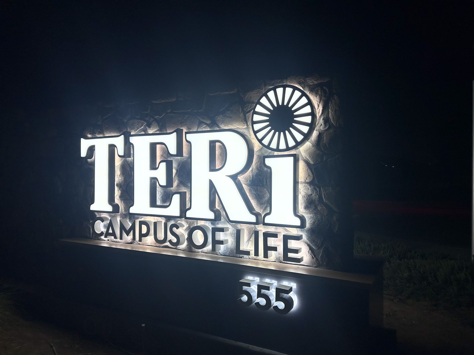 Illuminated sign for TERI Campus of Life, with address 555 at night.