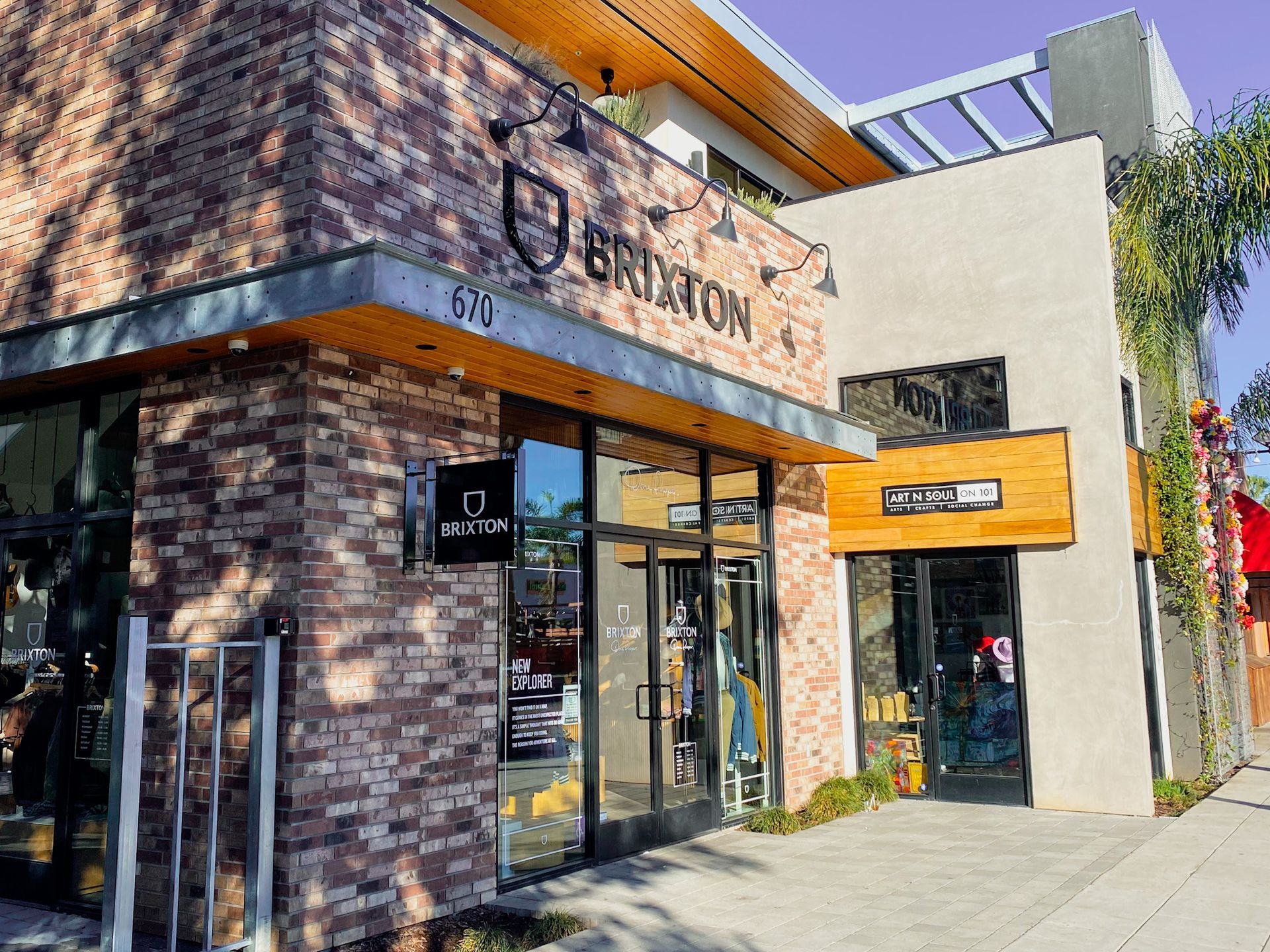 Brixton store exterior with brick and light-colored walls, glass doors, and a wooden sign.