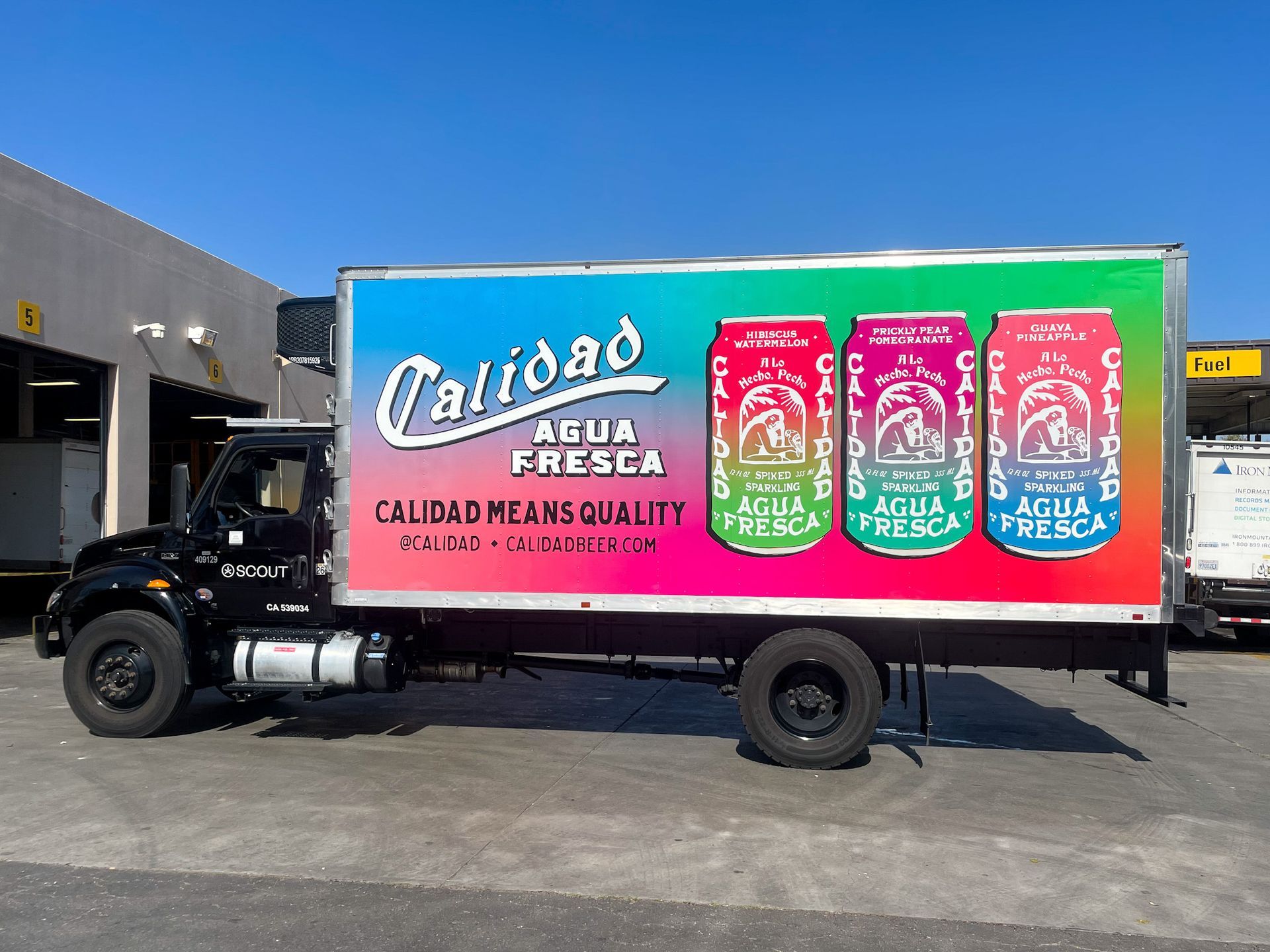 Calidad Agua Fresca truck with colorful can graphics parked in a lot. 