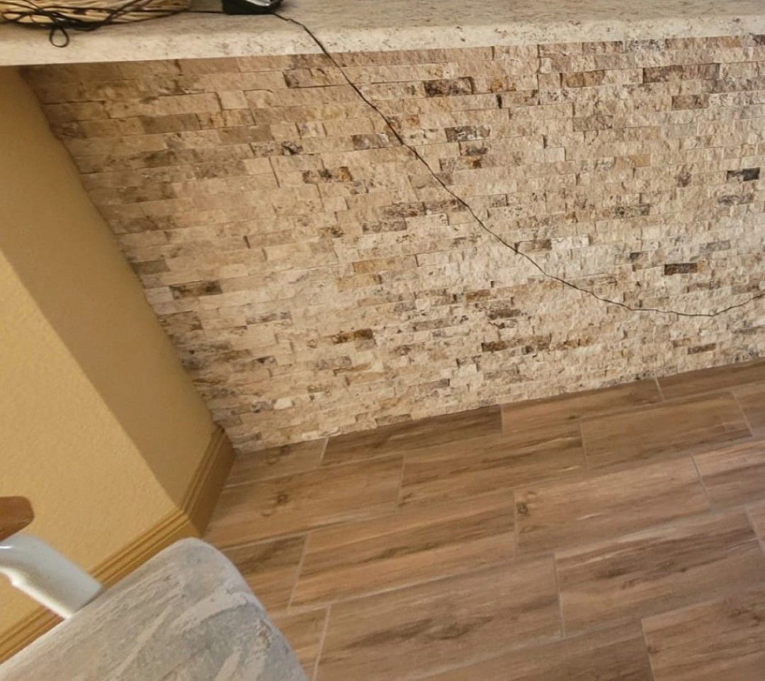 A kitchen with a brick wall and a wooden floor.