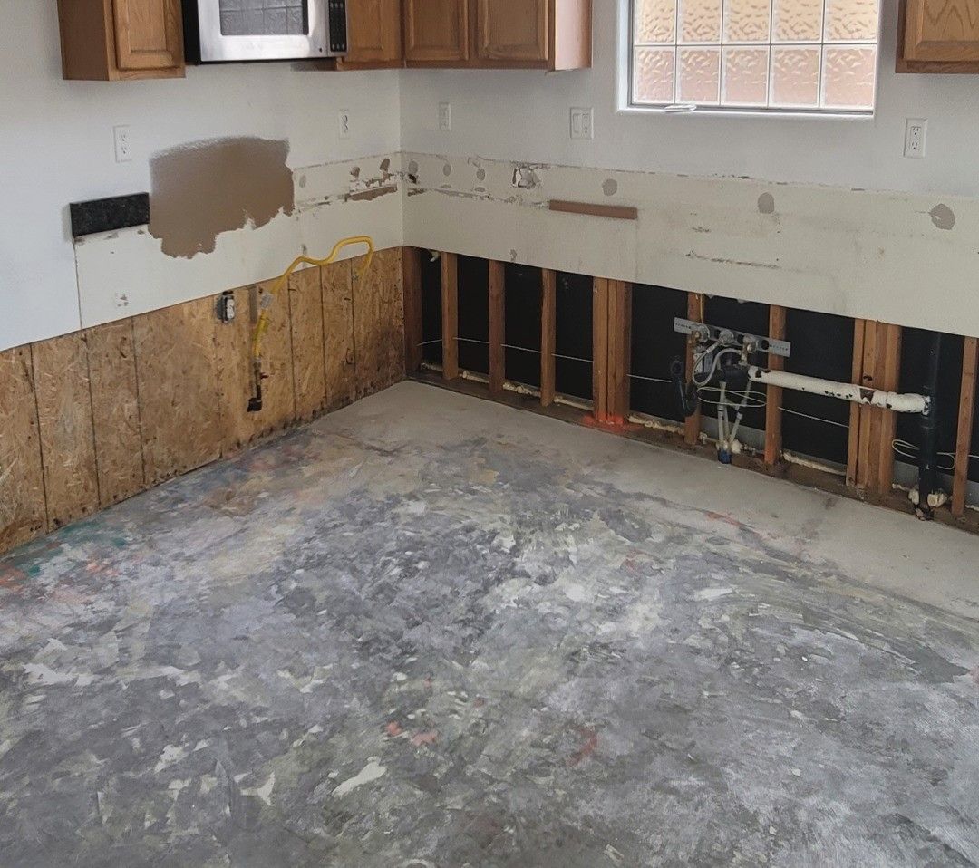 A kitchen with wooden cabinets and a concrete floor.