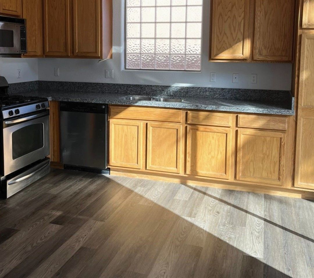 A kitchen with wooden cabinets , stainless steel appliances , and a window.