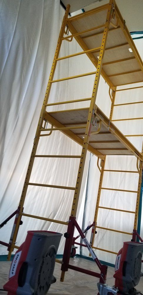 A yellow scaffolding is sitting in front of a white curtain.