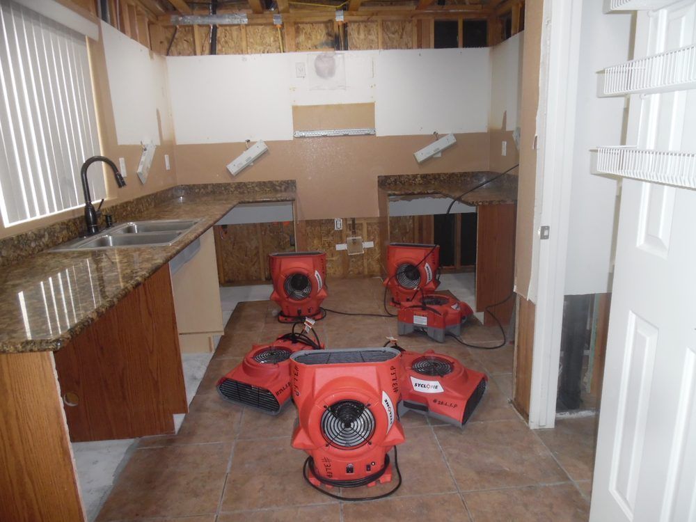 A kitchen under construction with a lot of red fans on the floor.