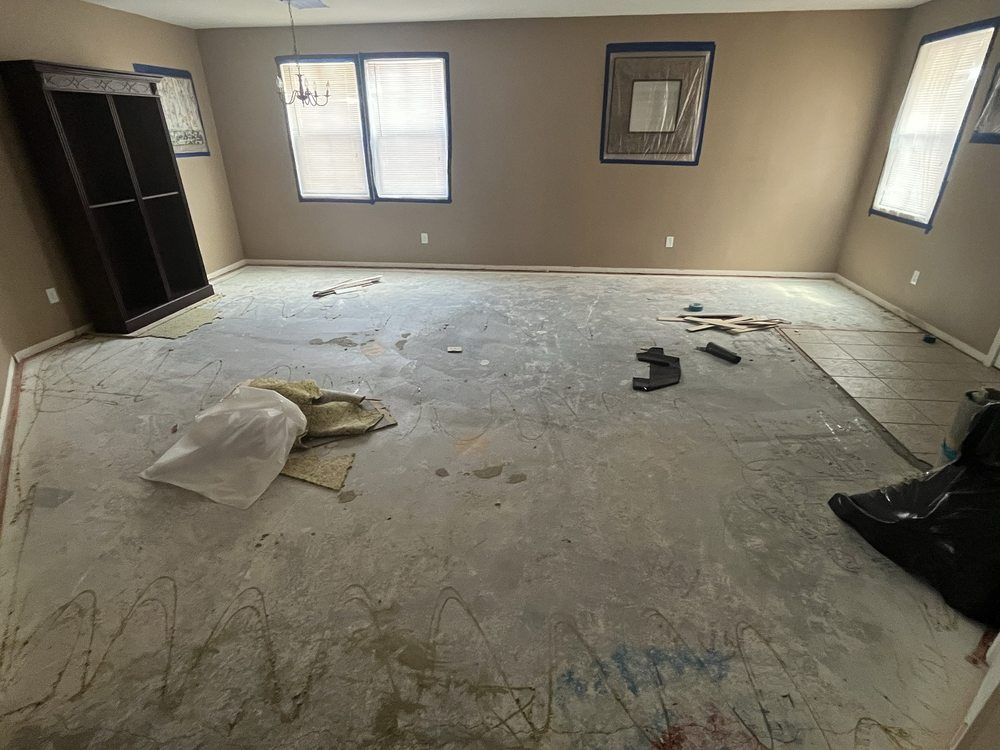 A large room with a dirty floor and a lot of windows.