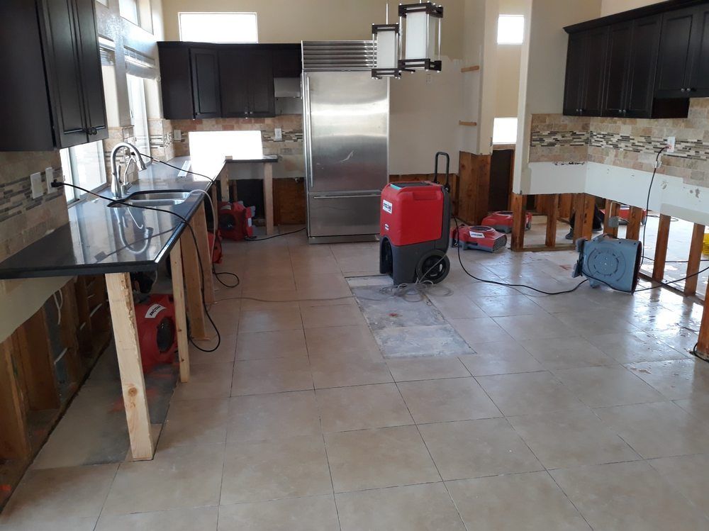 A kitchen with a stainless steel refrigerator and a red vacuum cleaner.