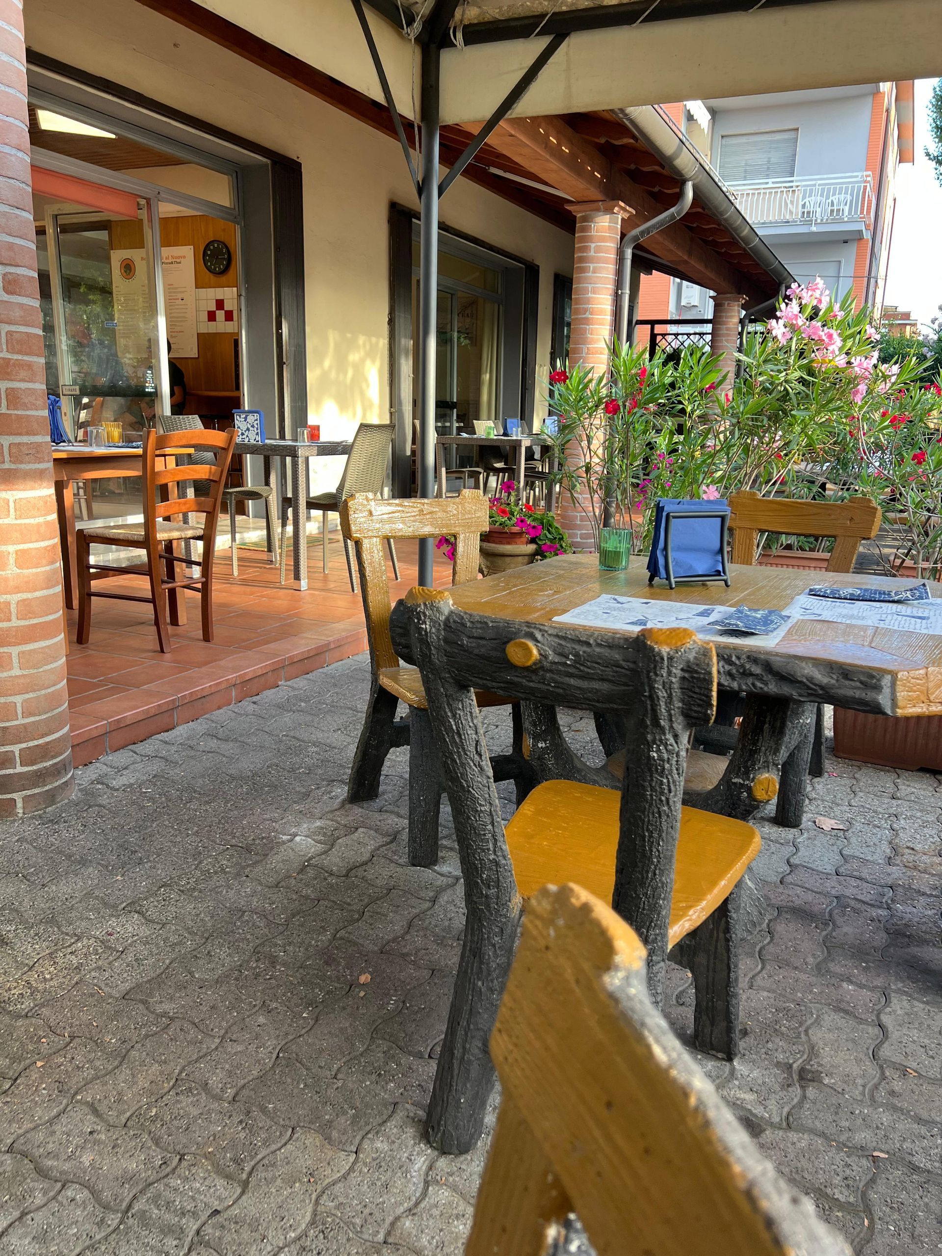 Un patio con tavoli e sedie sotto un ombrellone