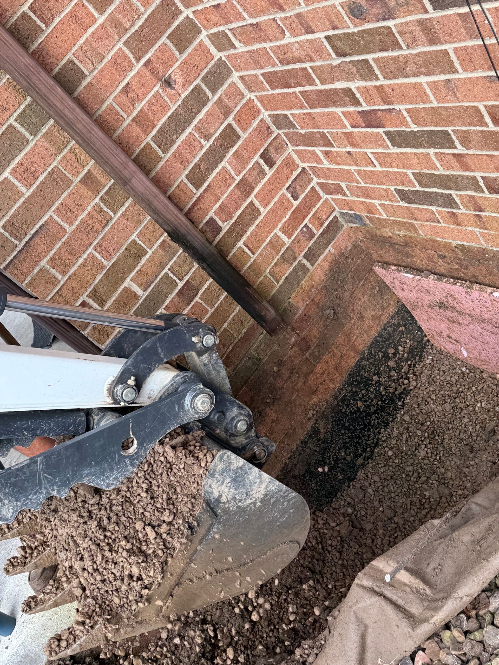 A man is driving a small excavator in a park.