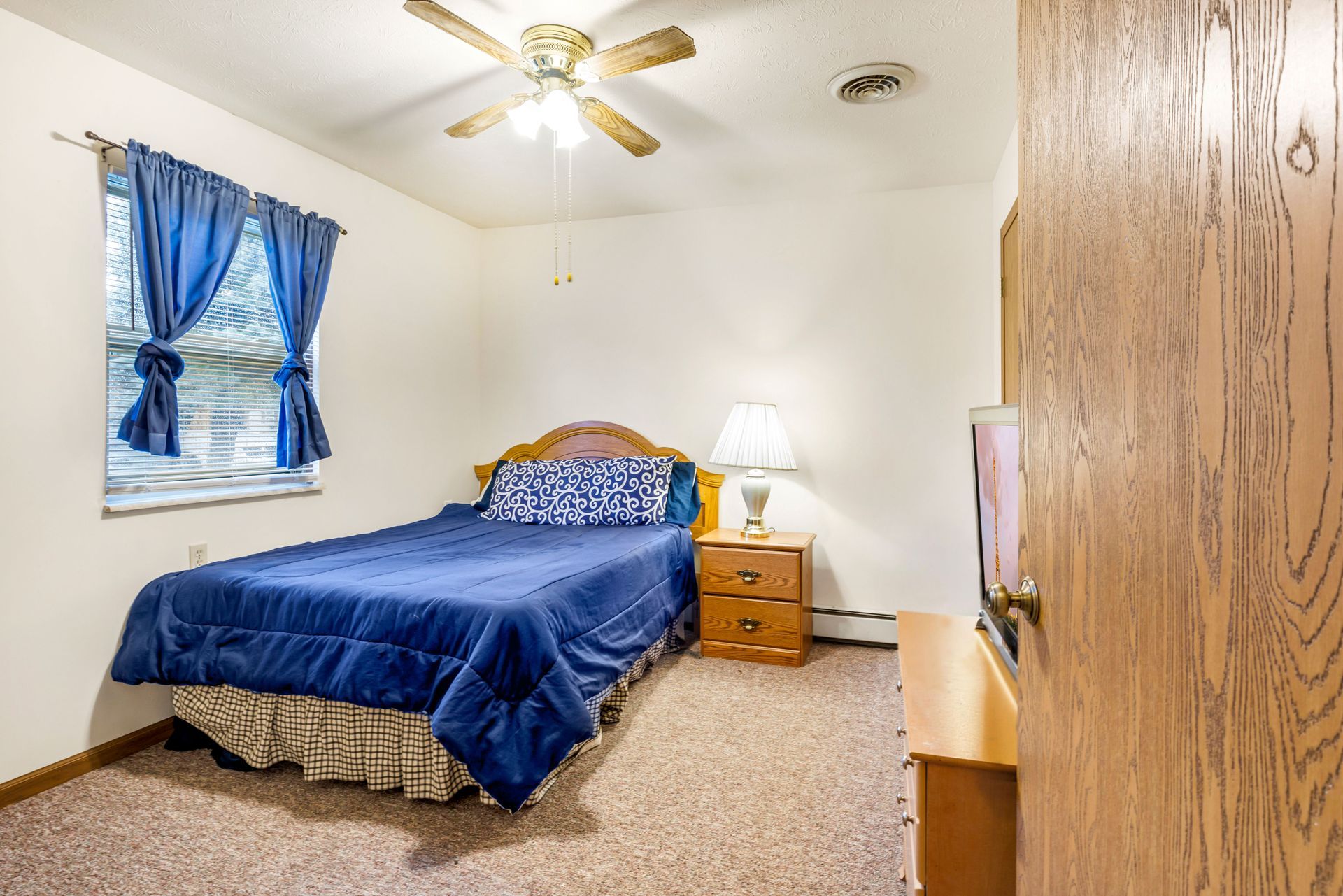 A bedroom with a bed , nightstand , dresser and television.