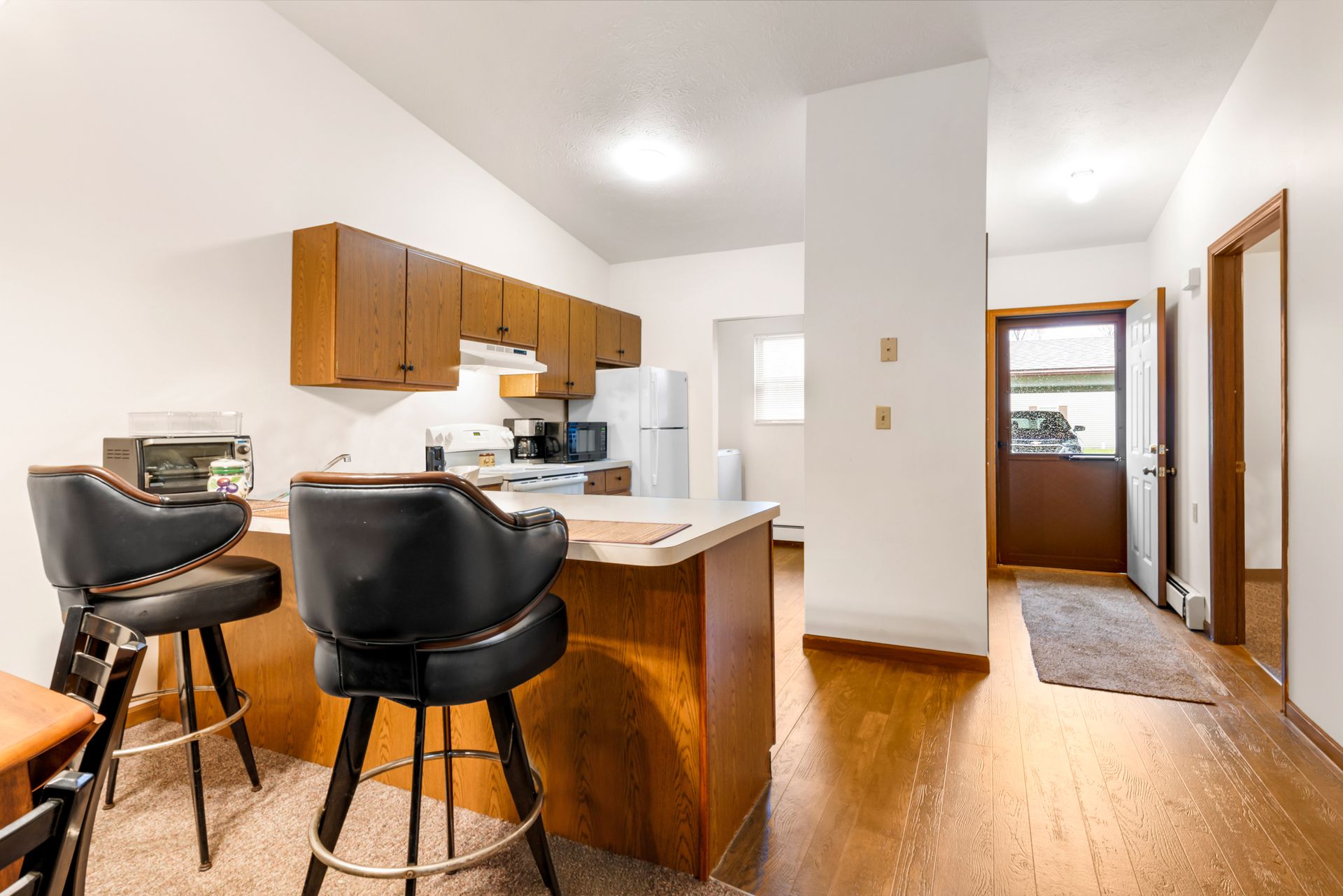 A kitchen with a bar and two bar stools in it.
