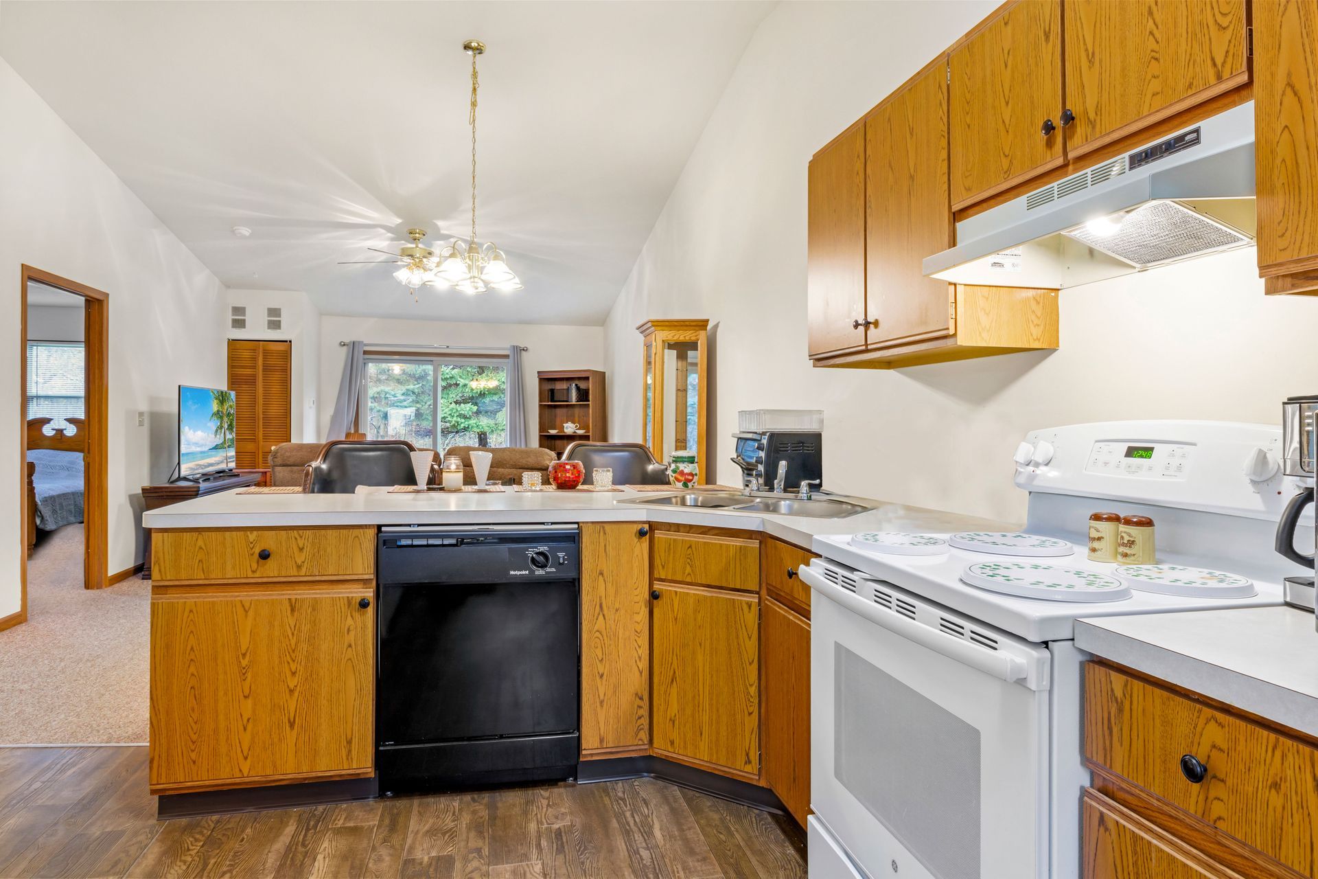 A kitchen with wooden cabinets , a stove , a dishwasher , and a sink.