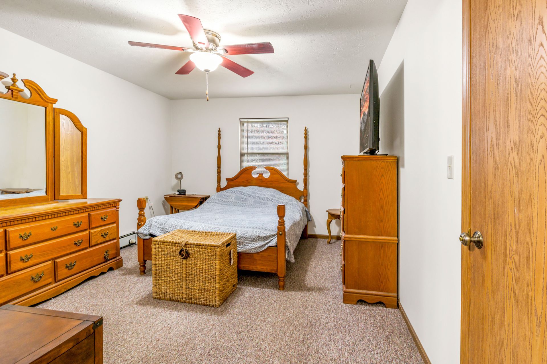 A bedroom with a bed , dresser , mirror and ceiling fan.