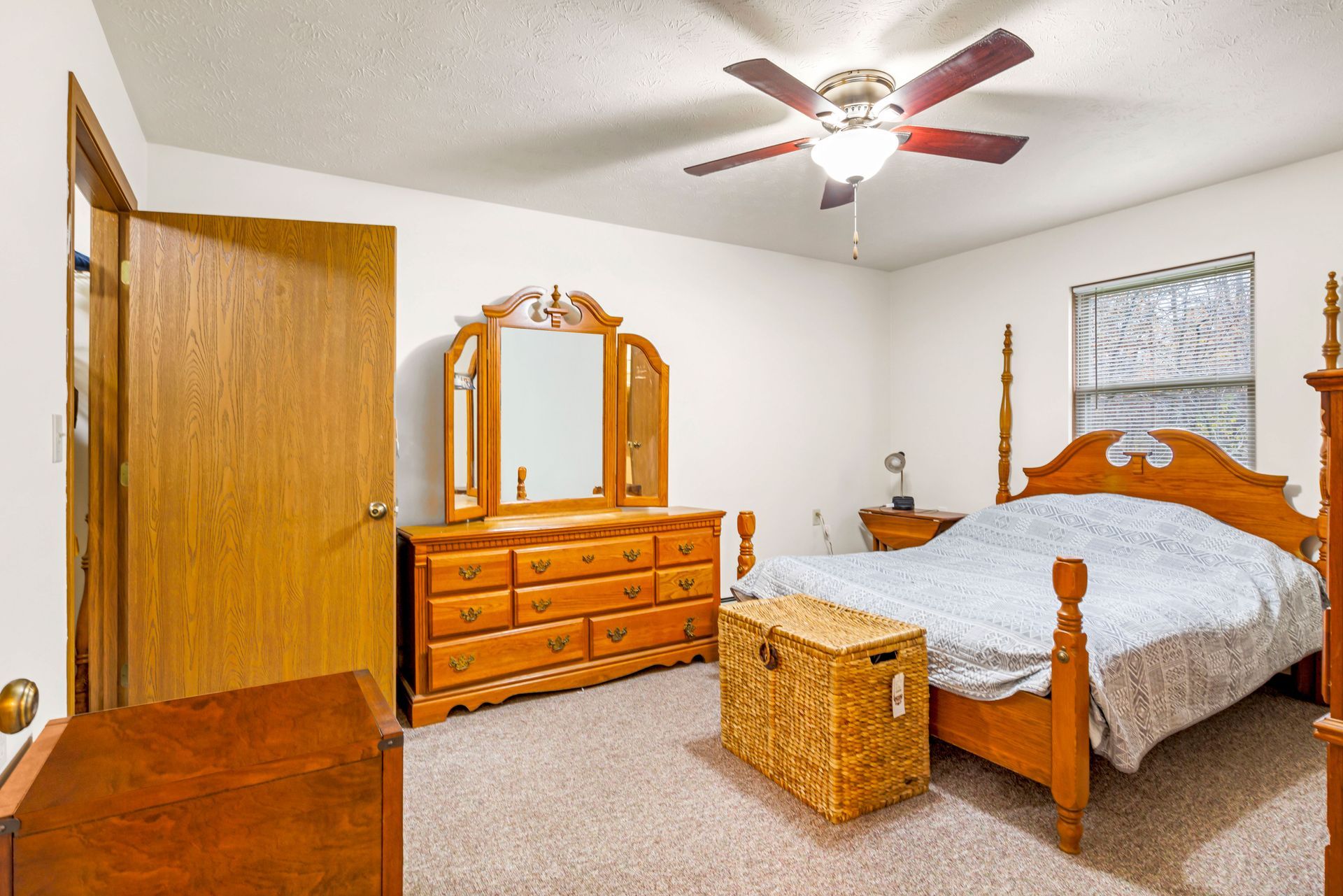 A bedroom with a bed , dresser , mirror and ceiling fan.