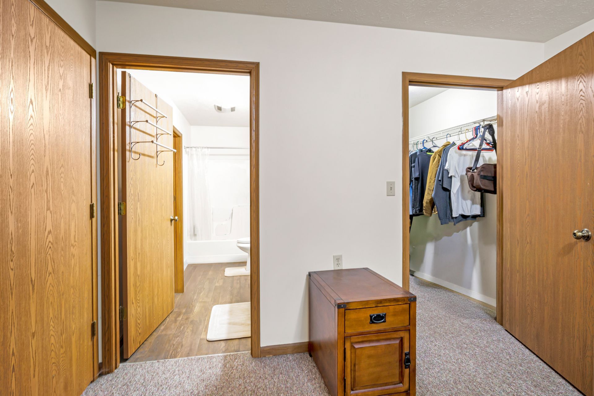 A bedroom with a dresser and a walk in closet.
