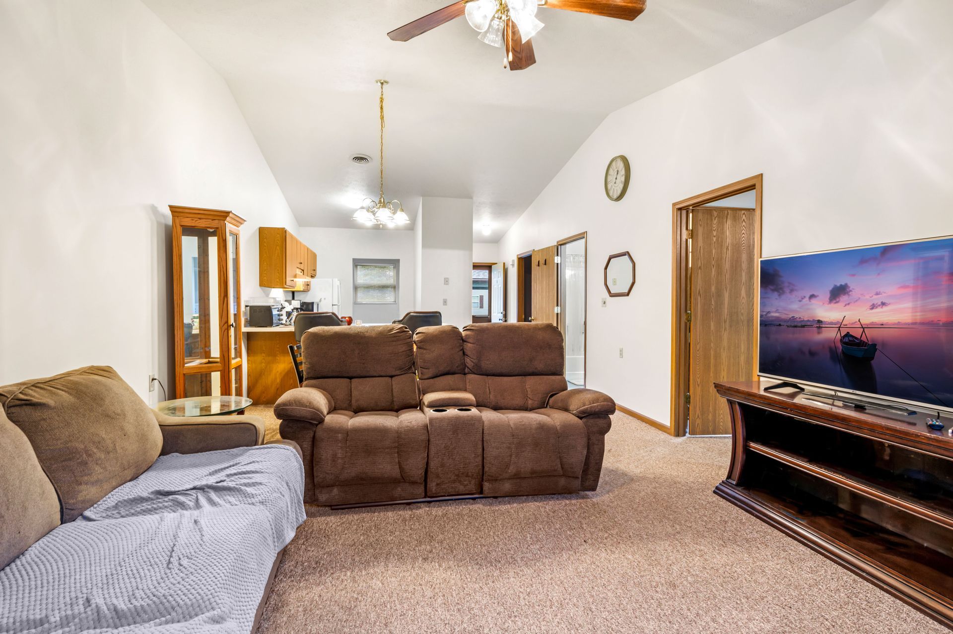A living room with a couch , television , and ceiling fan.