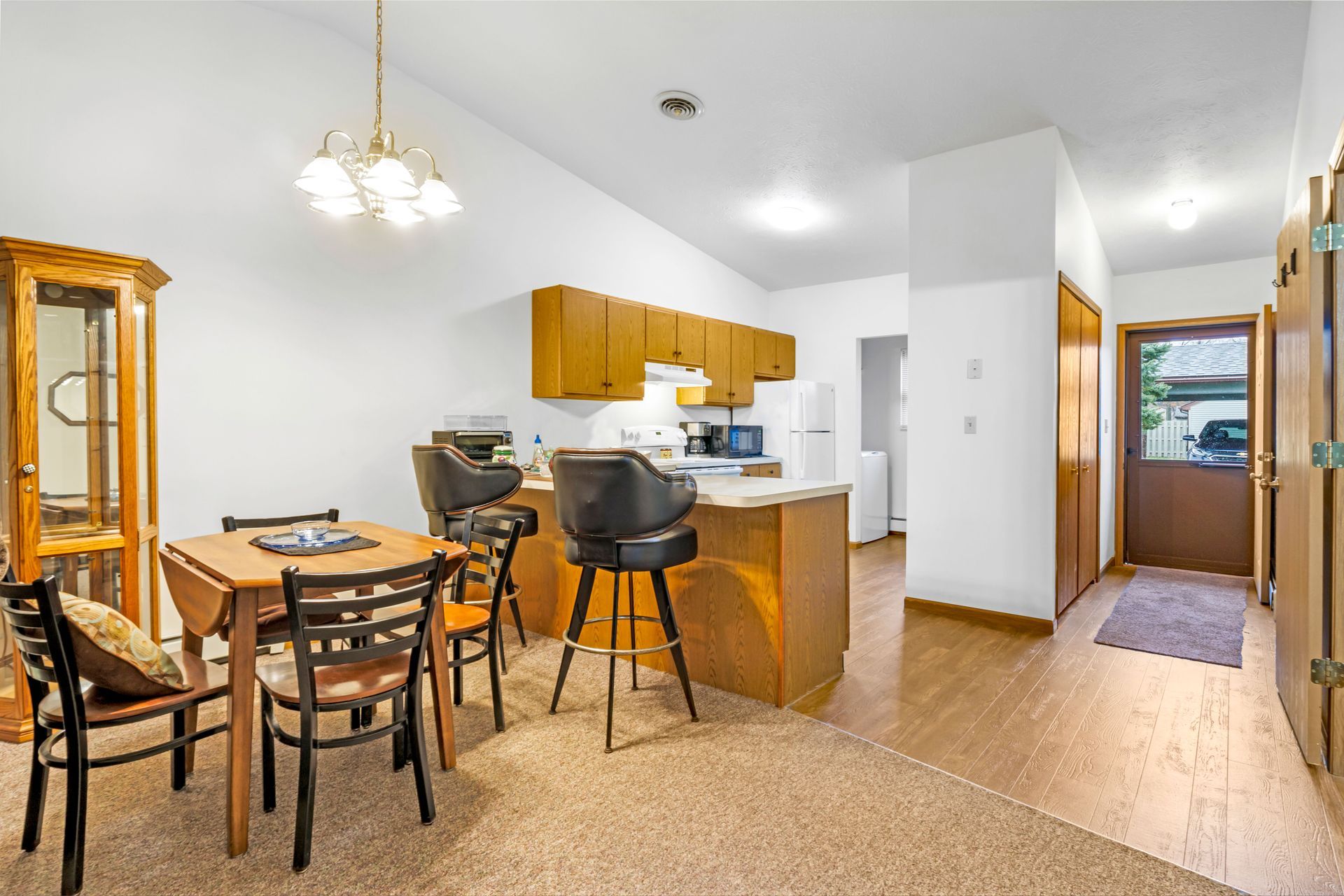 A living room with a table and chairs and a kitchen.