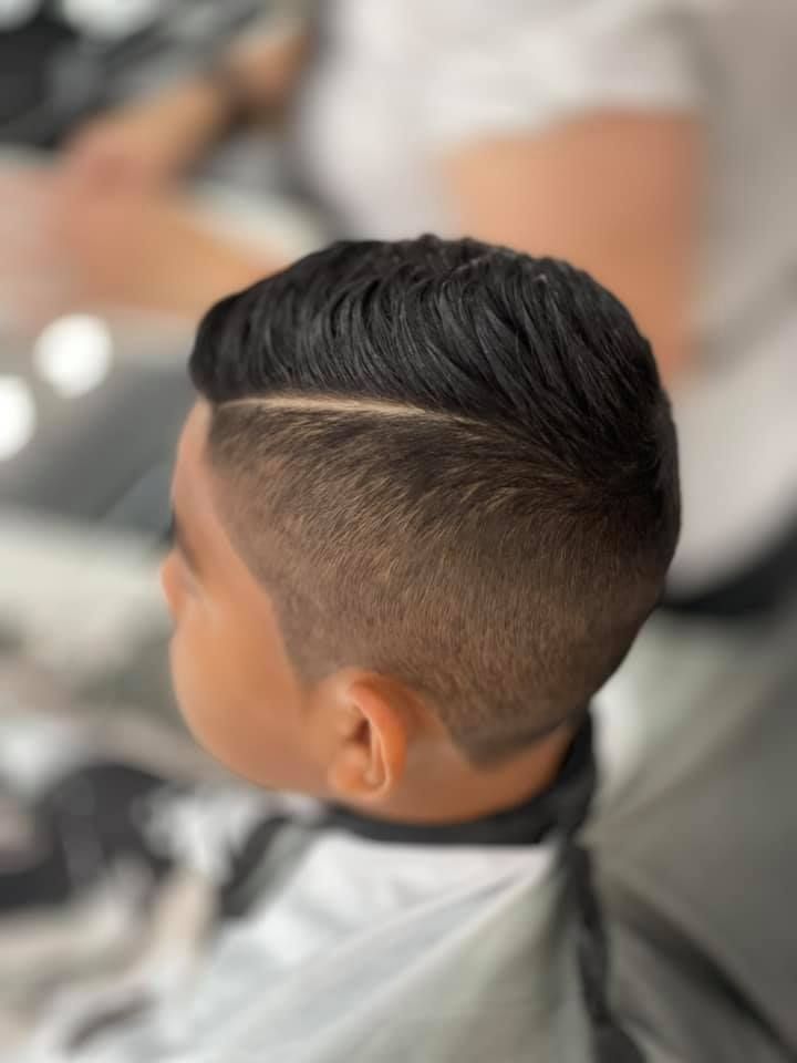A young boy is getting his hair cut at a barber shop.