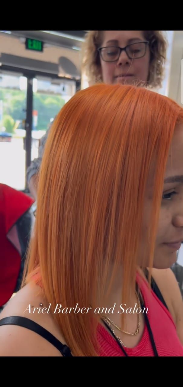 A woman with red hair is getting her hair cut by a hairdresser.