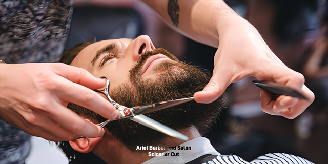 A man is getting his beard cut by a barber with scissors.