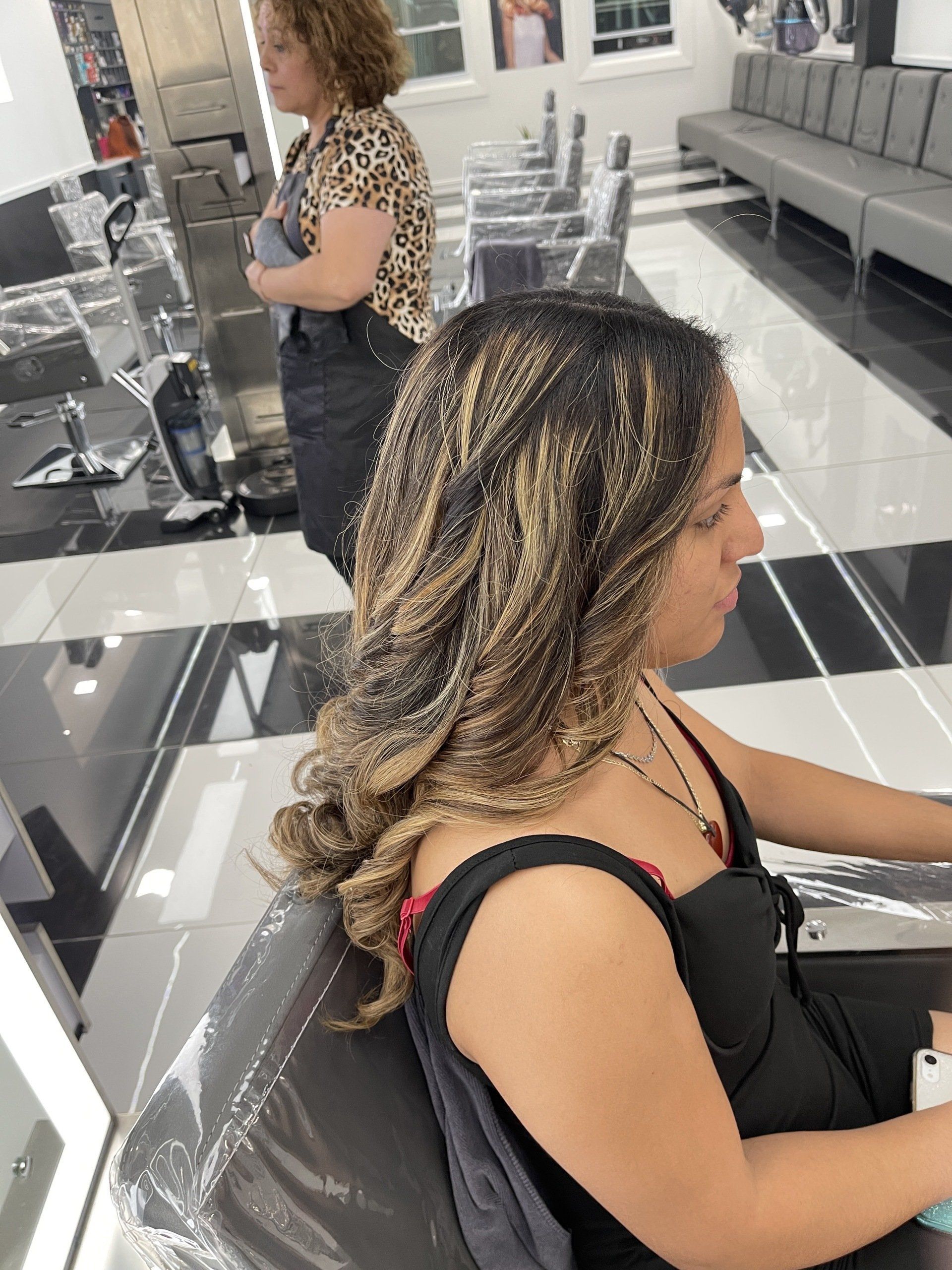 A woman is sitting in a chair at a hair salon.