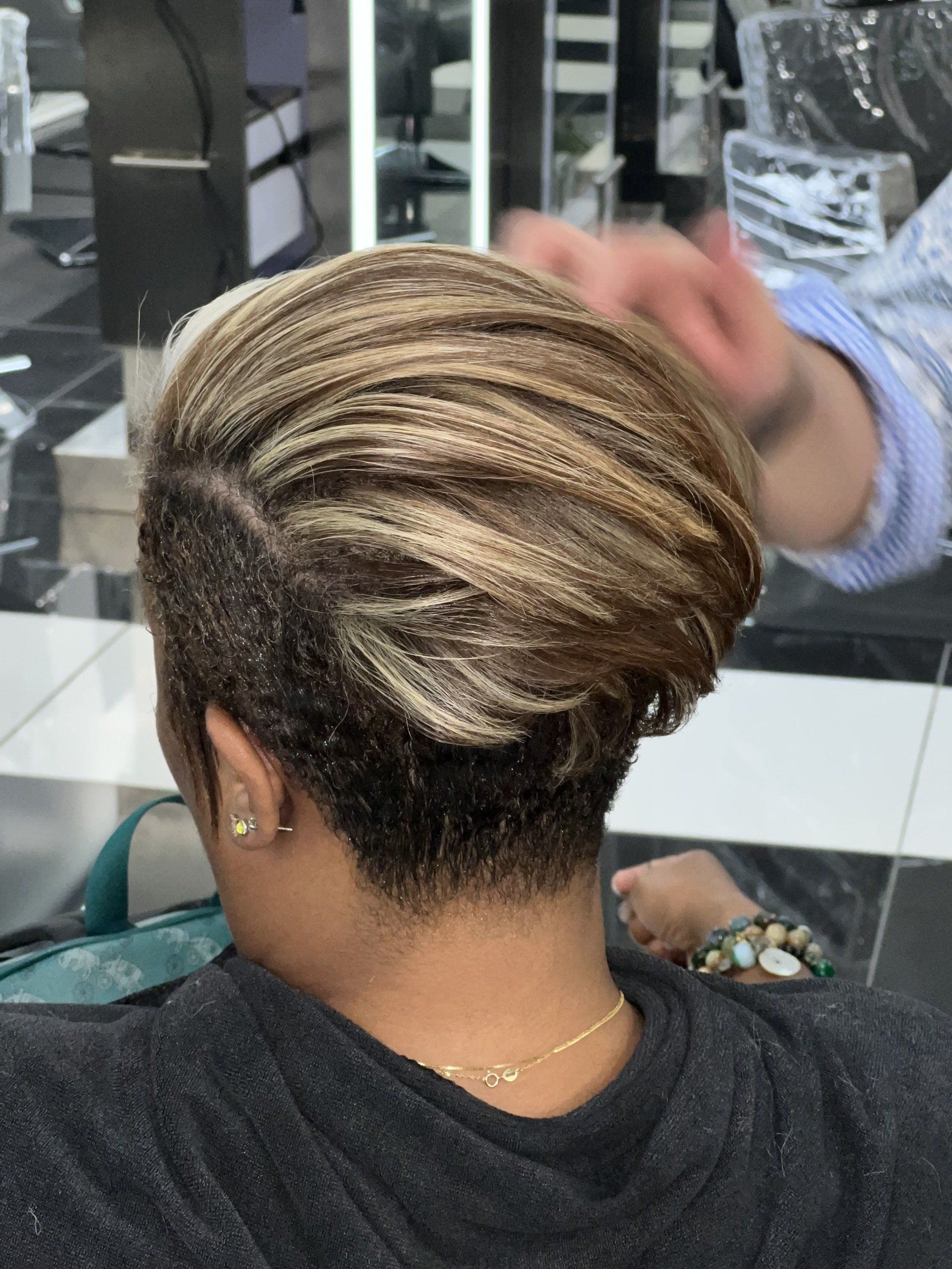 A woman is getting her hair braided in a salon