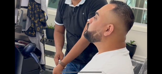 A man is getting his hair cut by a barber in a barber shop.