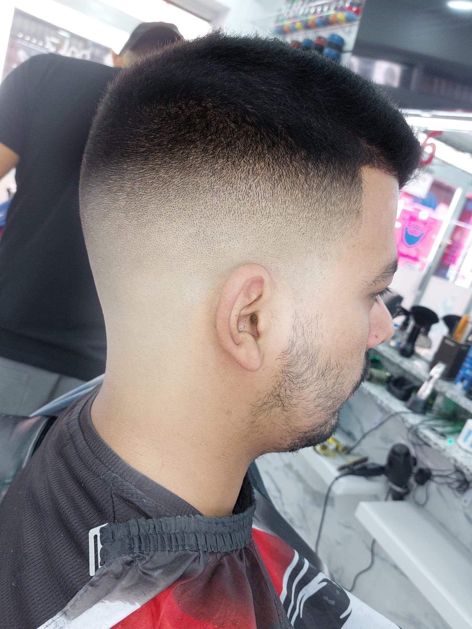 A man is getting his hair cut at a barber shop.