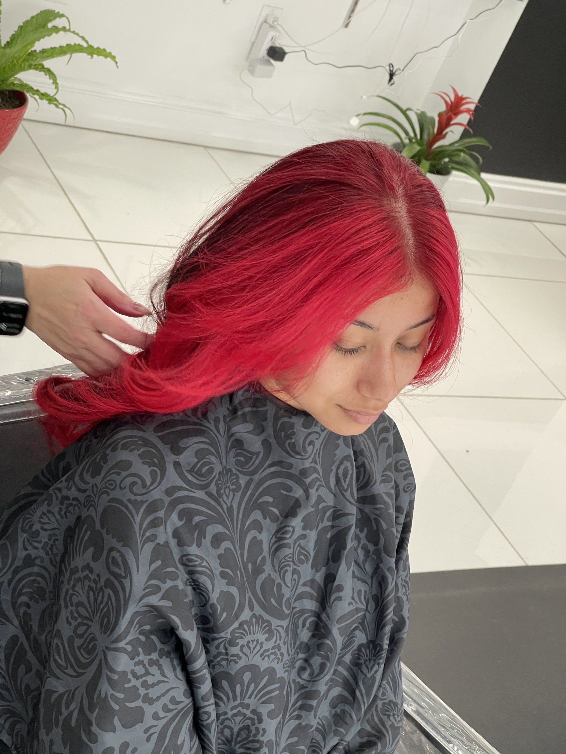 A woman with red hair is getting her hair dyed in a salon.