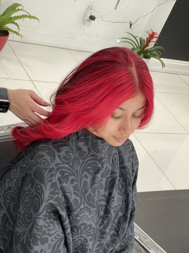 A woman with red hair is getting her hair cut by a hairdresser.