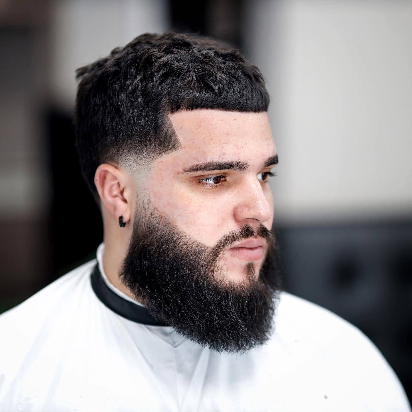 A man with a beard is wearing a white shirt.