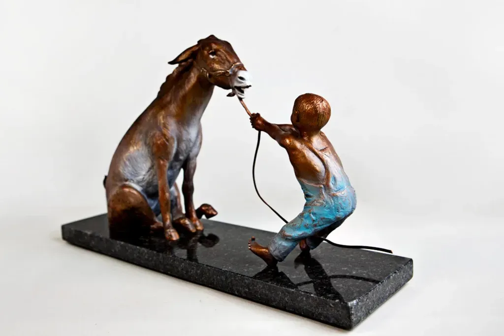 A bronze statue of a boy leading a horse on a leash