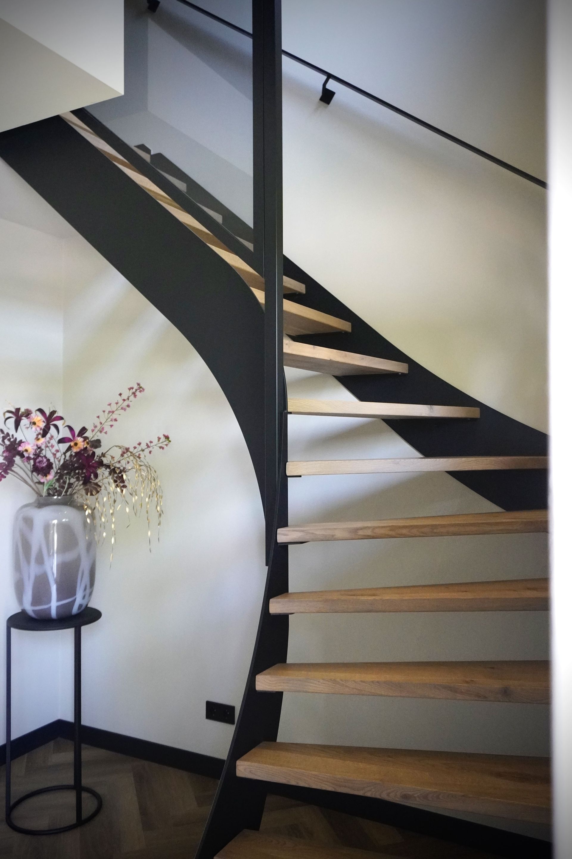 Zwart metalen trap met houten treden, uitgevoerd met onderkwart