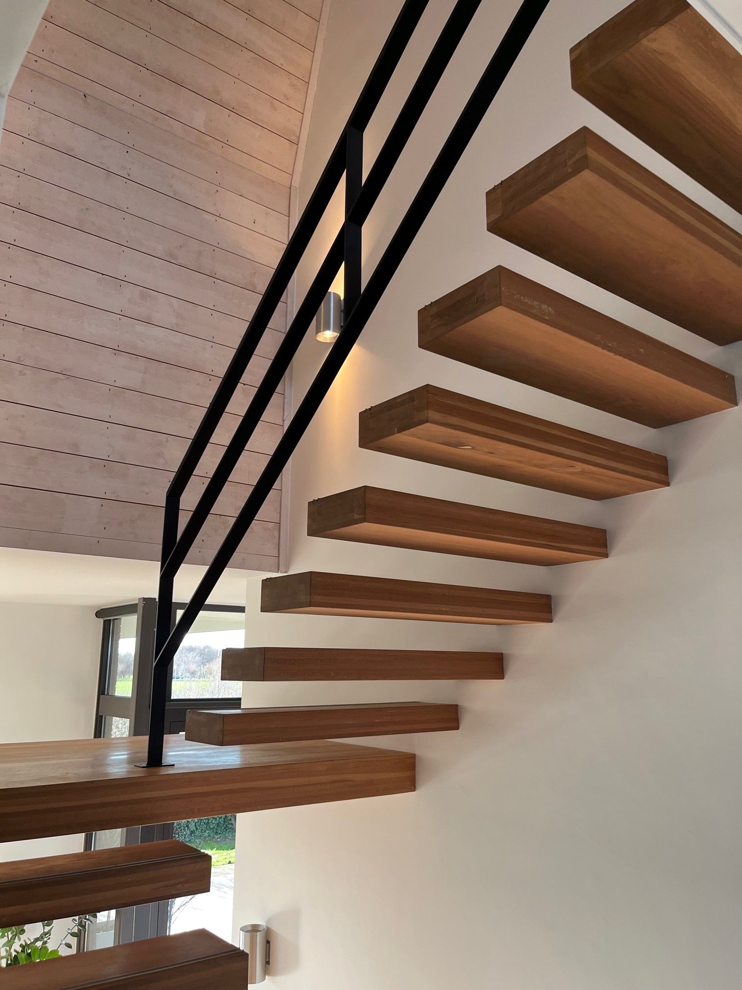 Stalen balustrade naast zwevende eikenhouten trede