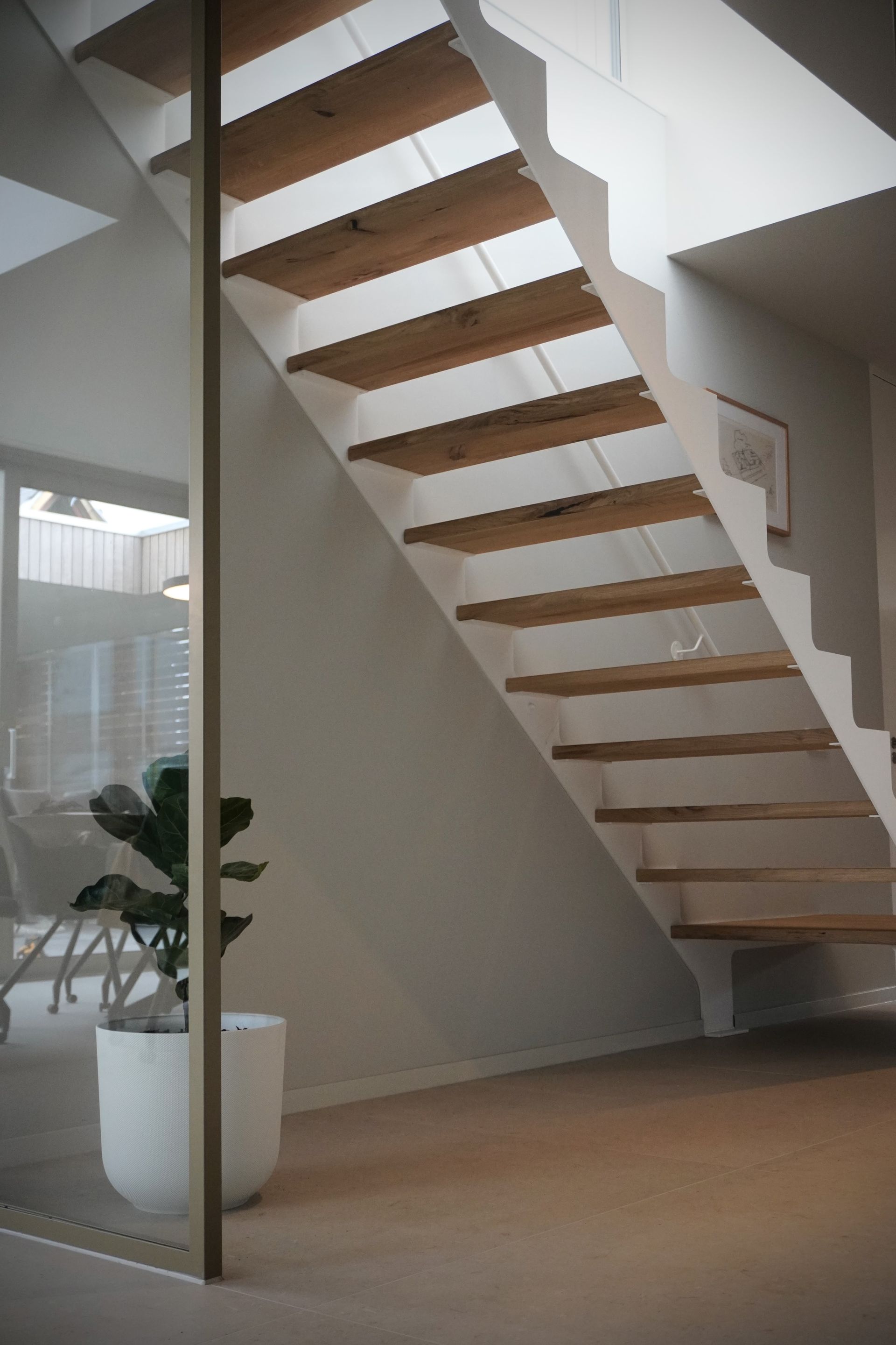 Stalen midden-boom trap met glazen balustrade en eiken treden