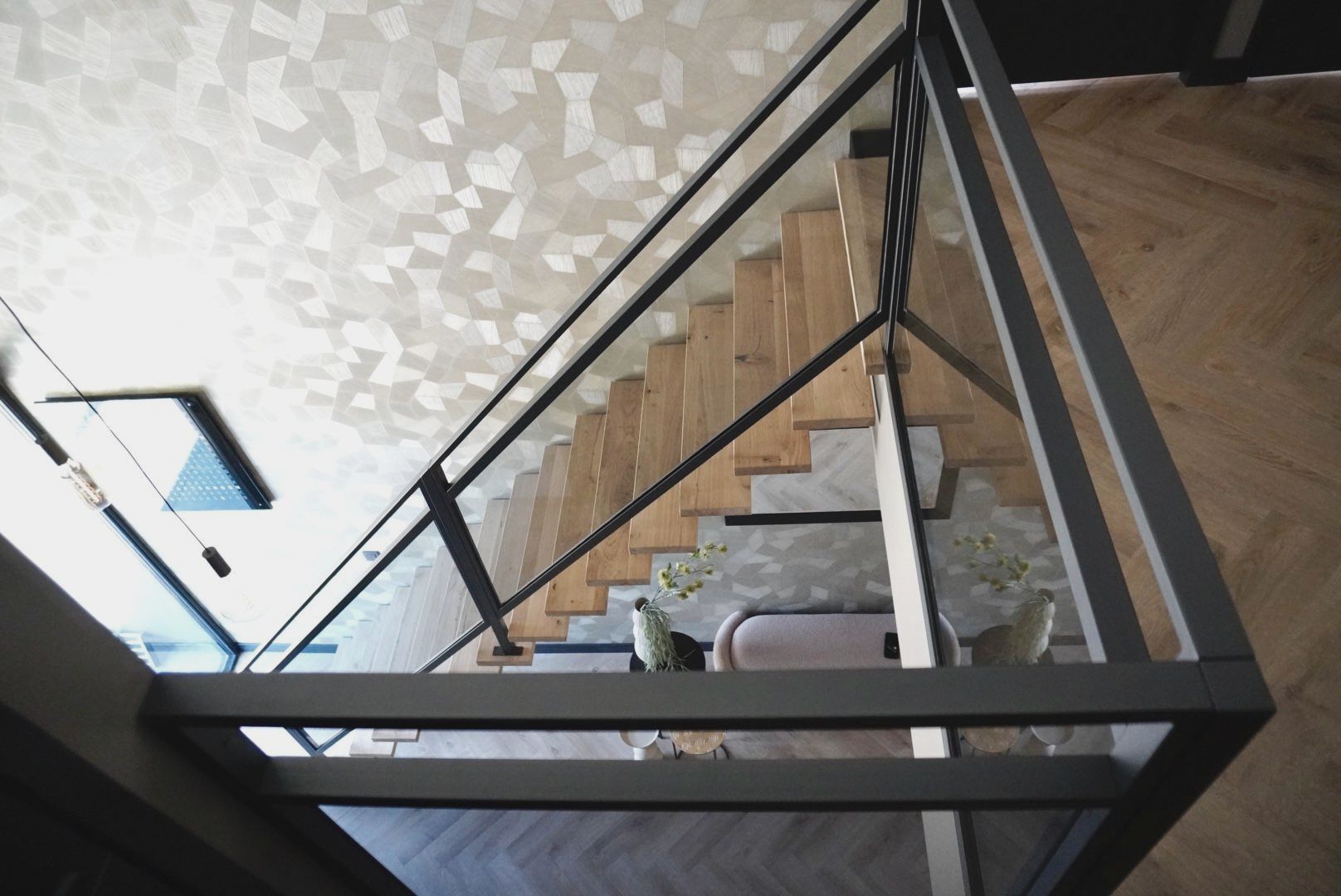 Stalen middenboom trap met eiken treden en een glazen balustrade of traphek ernaast.