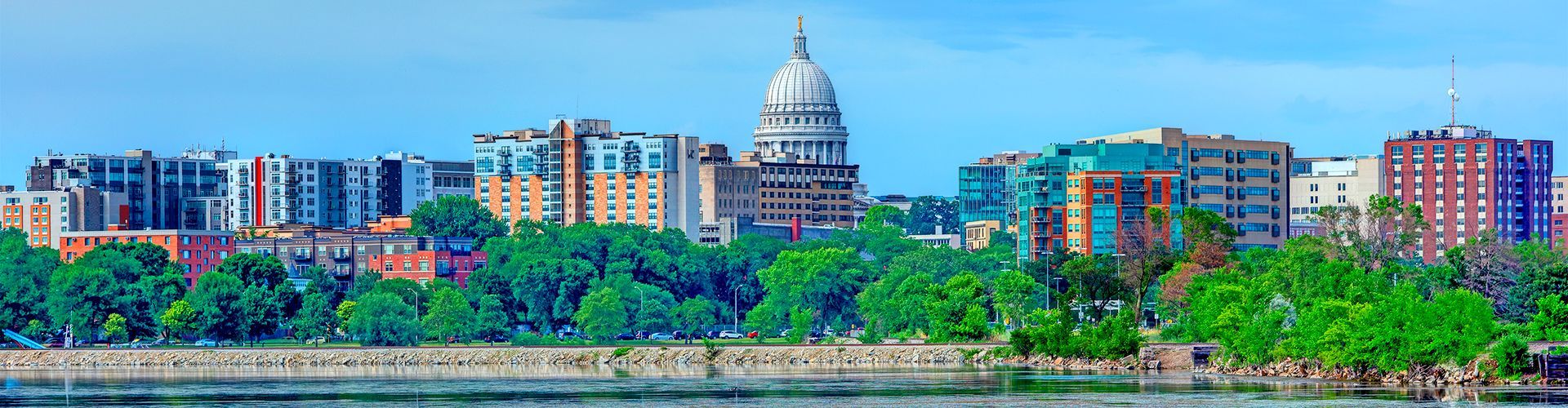 Panoramic view of the Madison, Wisconsin skyline, featuring the state capitol building dome surrounded by city architecture.