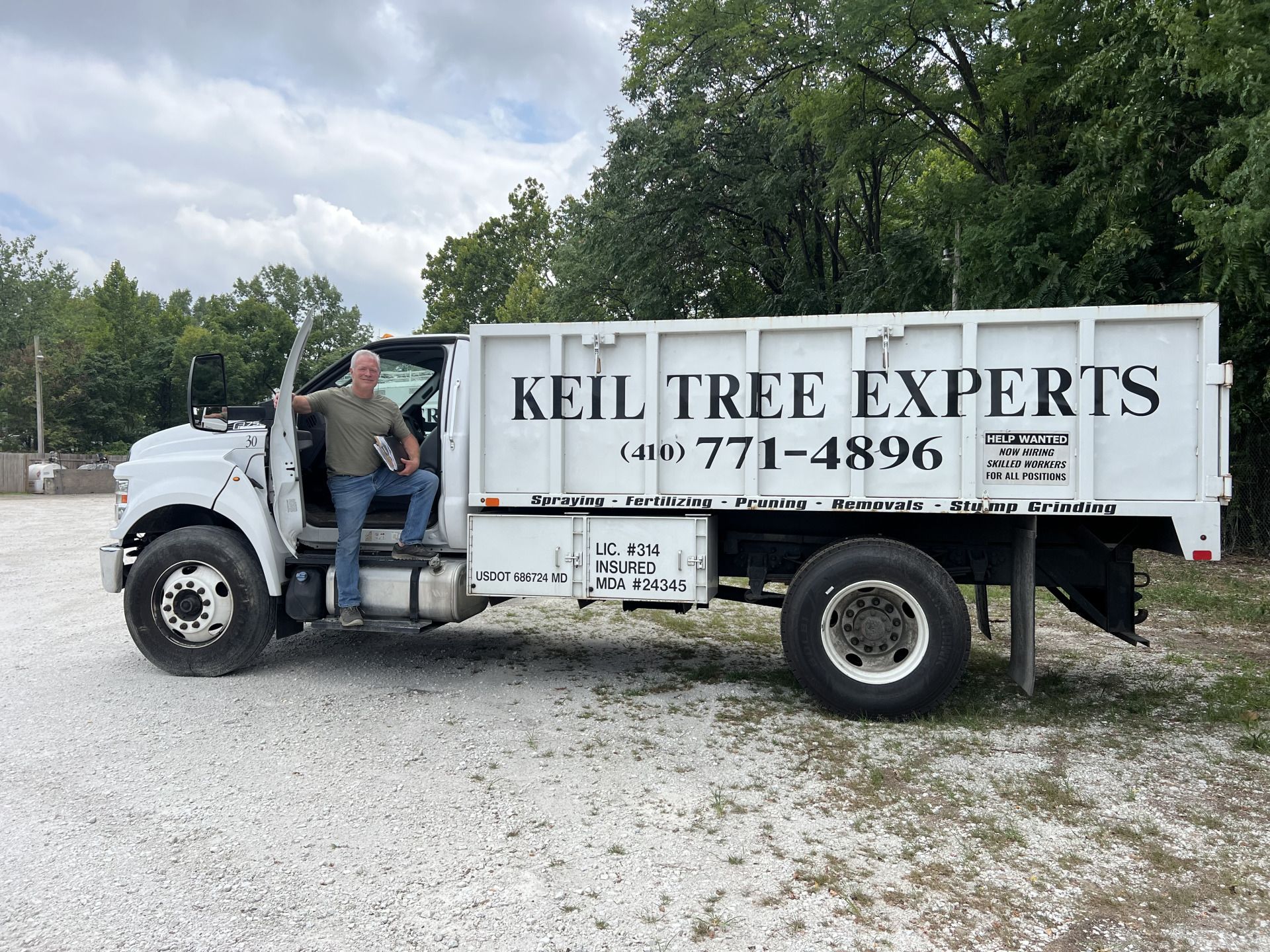 A man is sitting on the back of a keil tree experts dump truck.