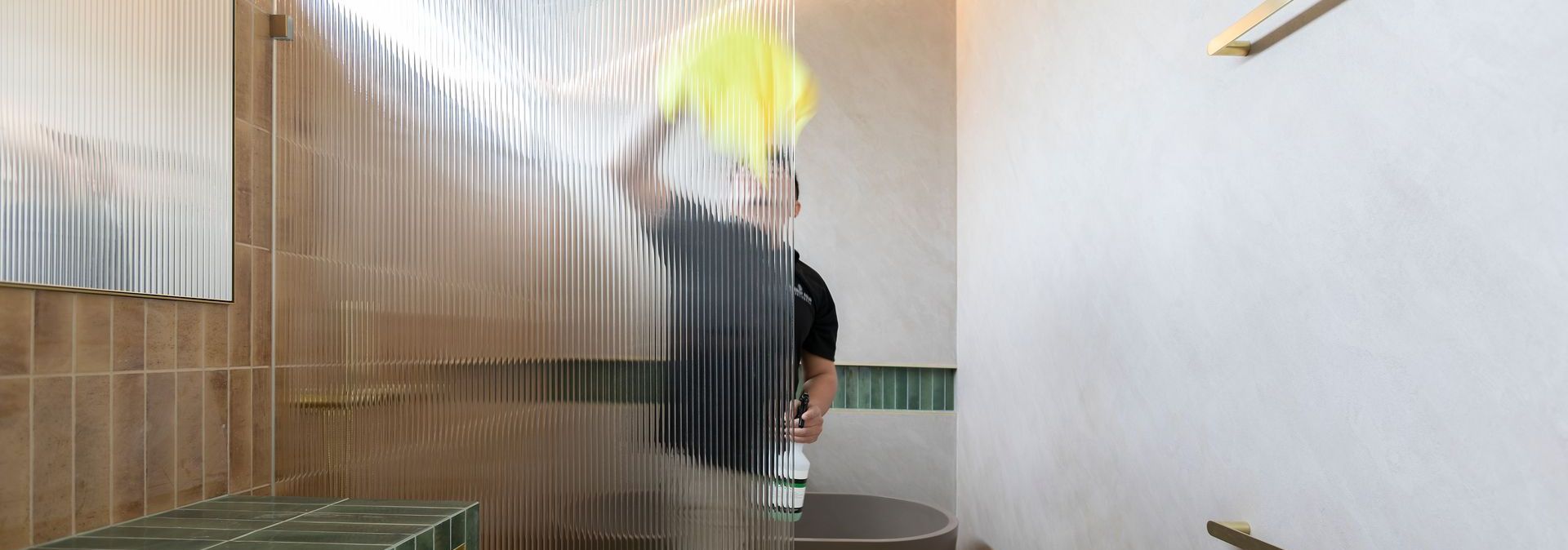 A man is standing in a bathroom holding a yellow towel.