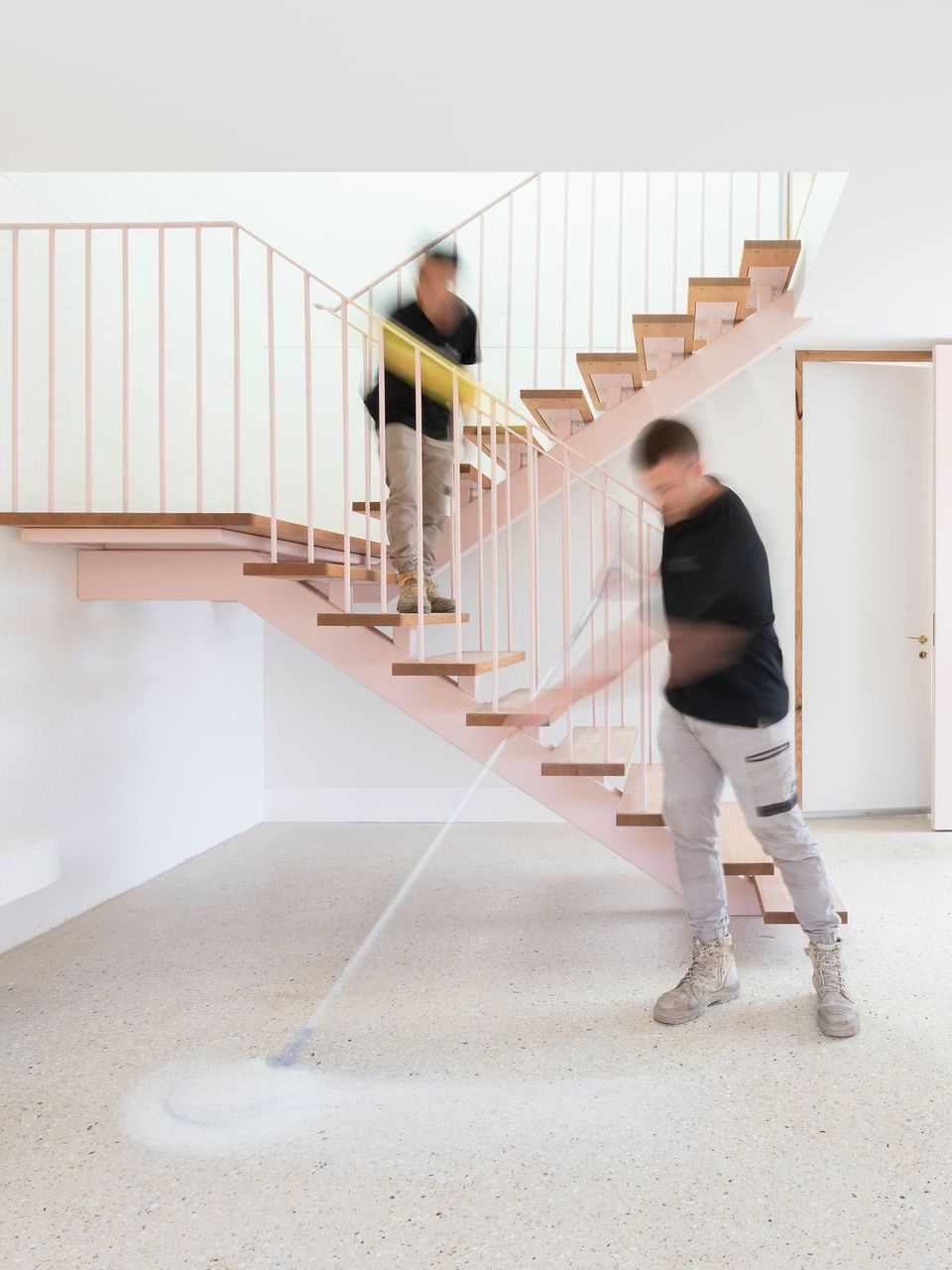 cleaner sweeping the floor next to a staircase