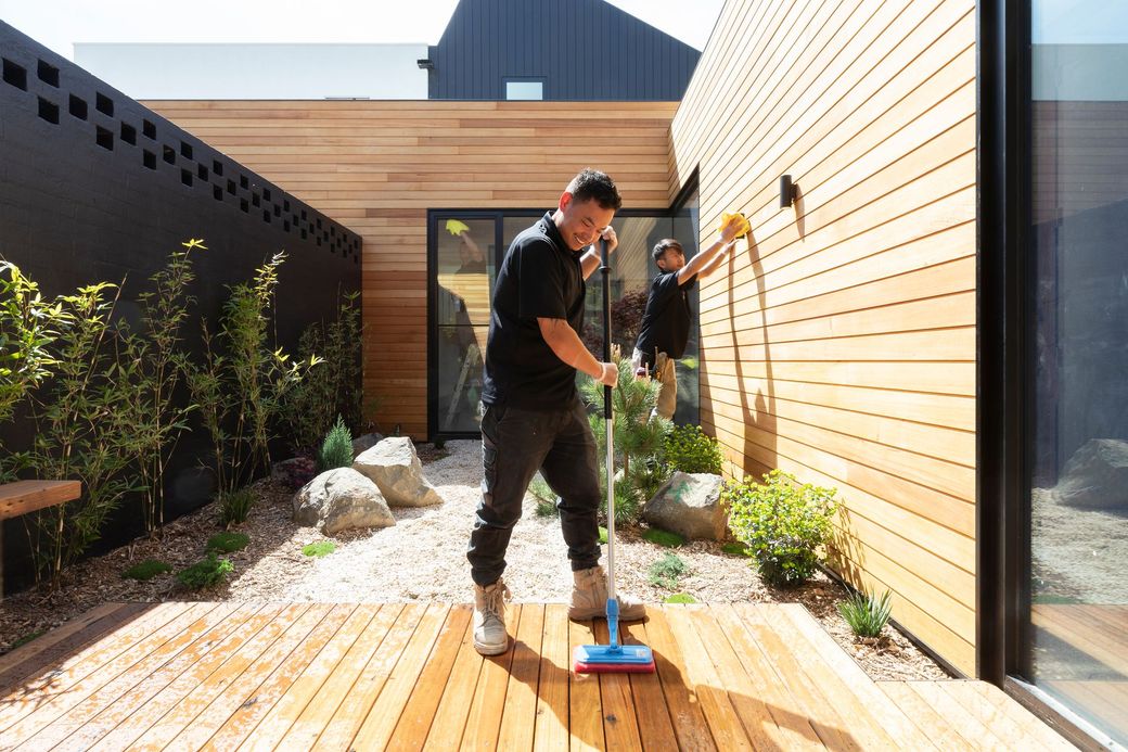 A man is cleaning a wooden deck with a mop.