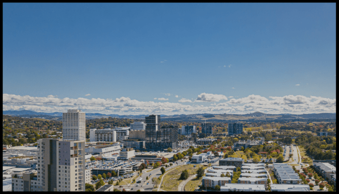 A man wearing a mask is coughing in front of a city skyline.